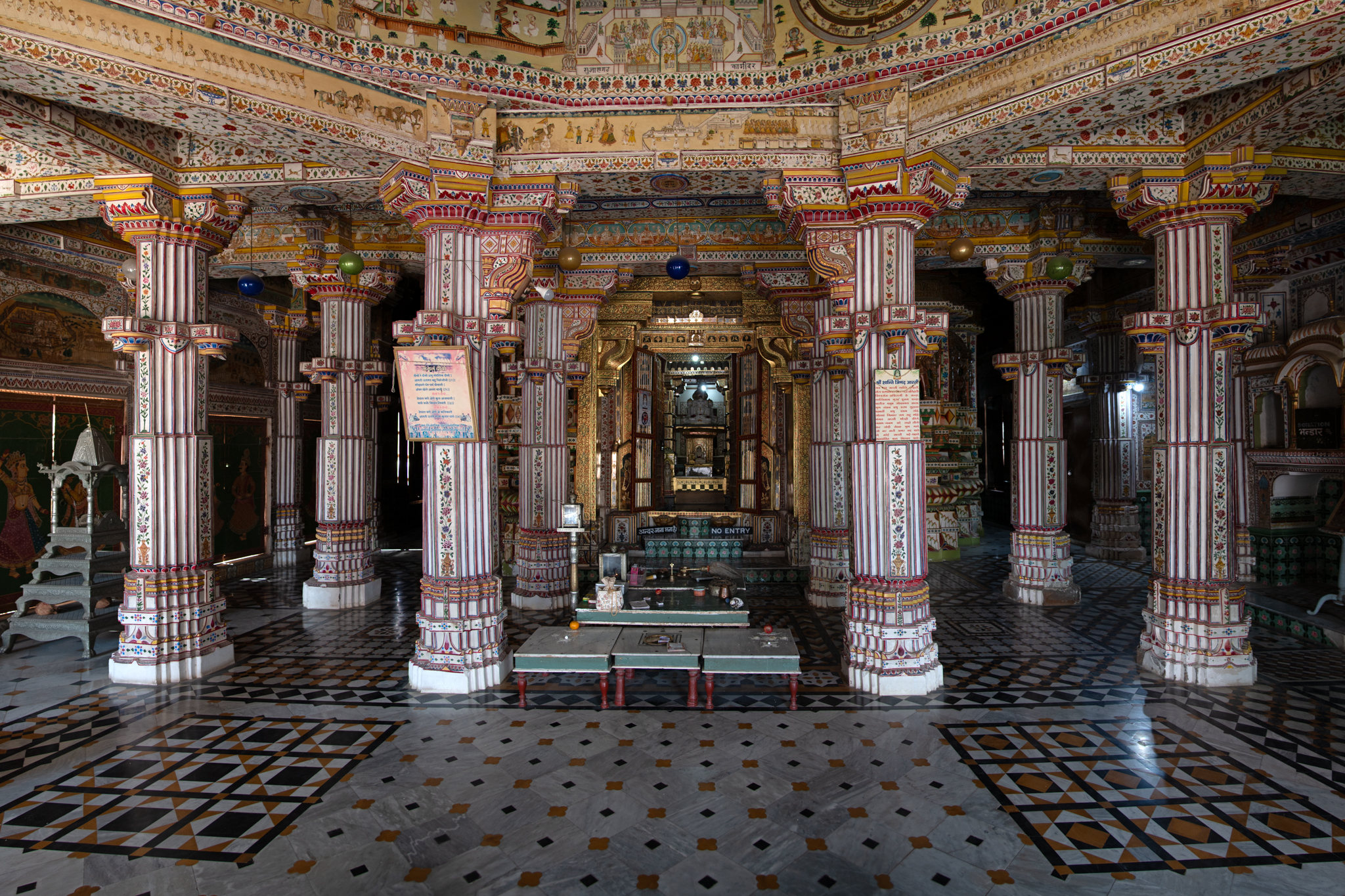 View of the east-facing mandapa of the temple. The mandapa has eight main pillars that support the central dome. Beyond this intercolumniation lies the main garbhagriha (sanctum sanctorum) which enshrines Sumatinatha Tirthankara. All the wall and pillar surfaces are painted.