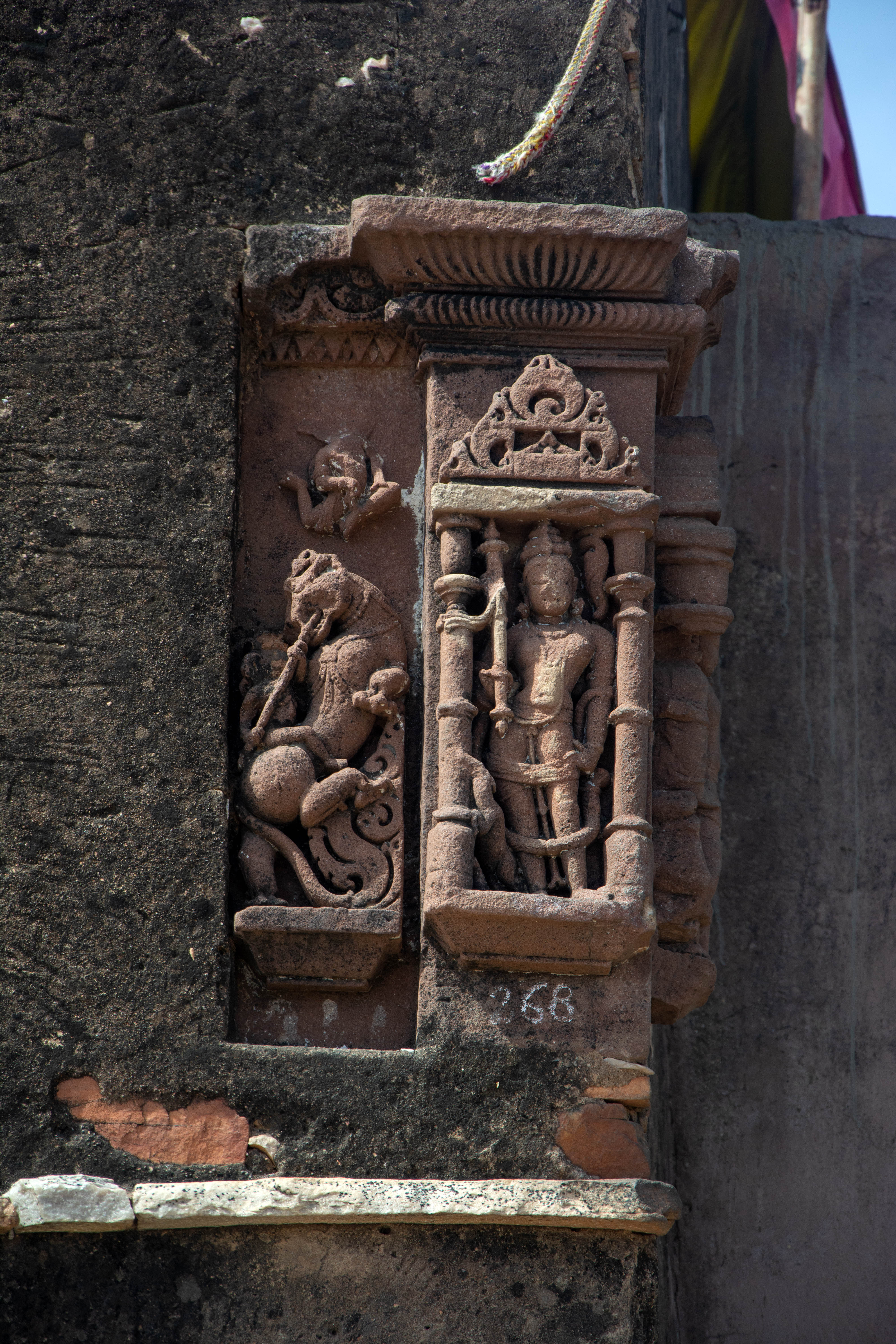 On the main offset, there is a carved image of a directional deity inside the niche, such as Vayu. In the recess, there is a vyala figure and a lion rider. It is affixed to a late structure.