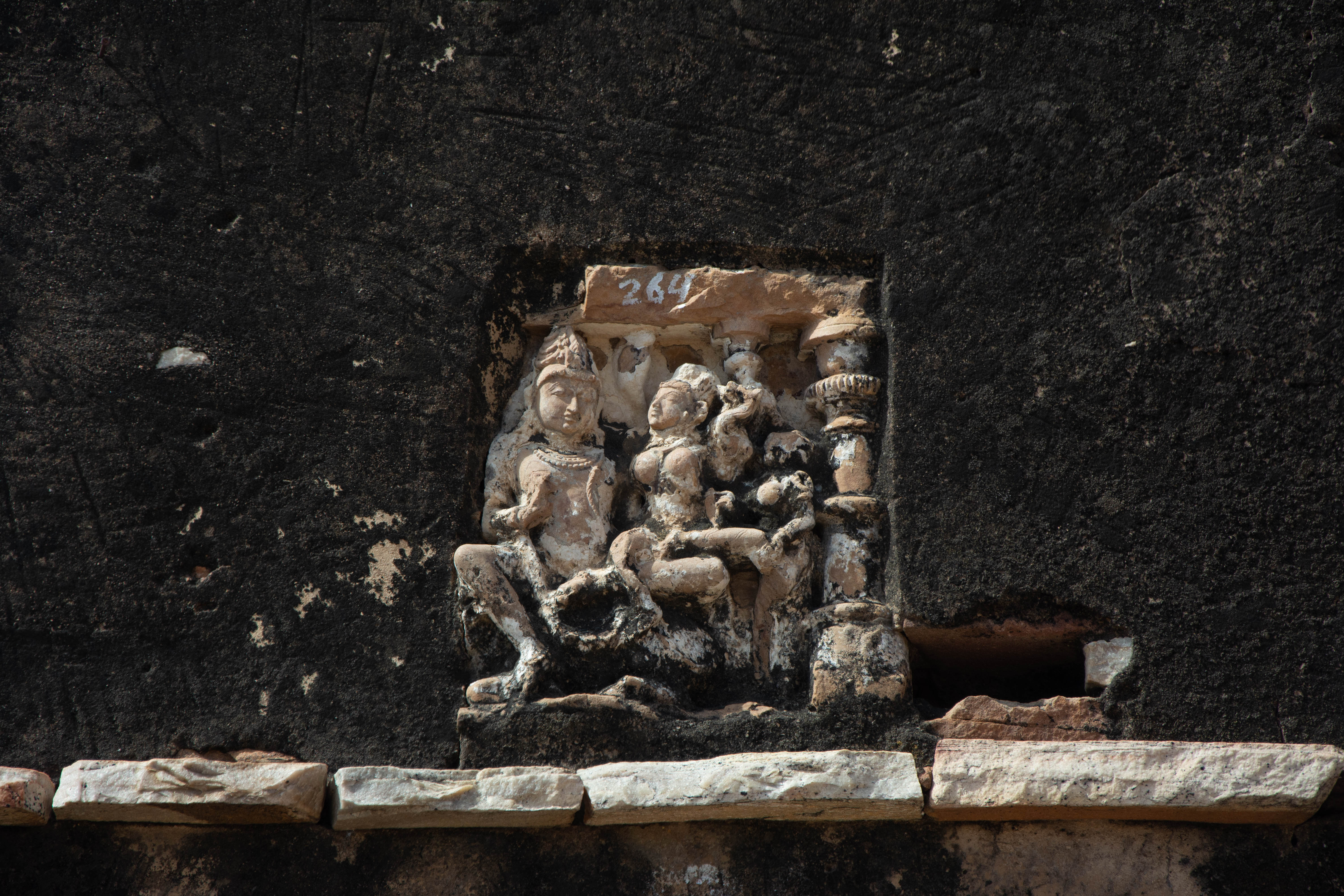 A niche contains a figure of Uma Maheshwar. Shiva sits in the lalitasana posture, comforting Parvati in his lap. It is affixed to a late structure.