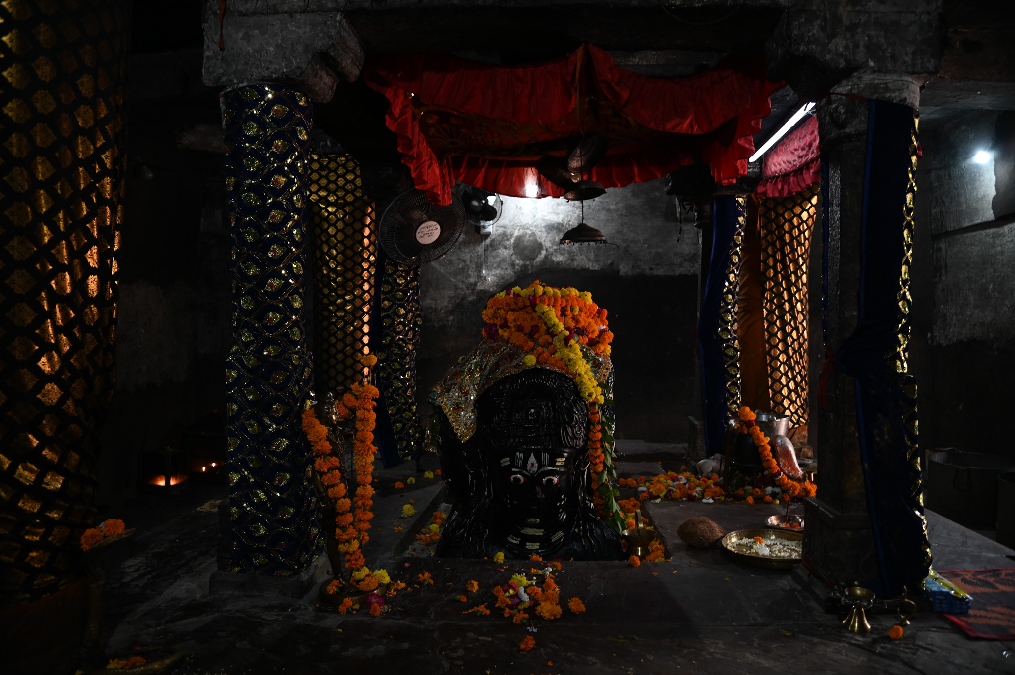 On the south side of the linga, one can observe the deity's face and bust. The deity has a heavy jatamukuta (matted crown) on its head, as well as hairlocks coming down to the shoulders. The sringara (attributes) of all four faces of the Chaturmukha linga are distinct, highlighting the iconographic features.