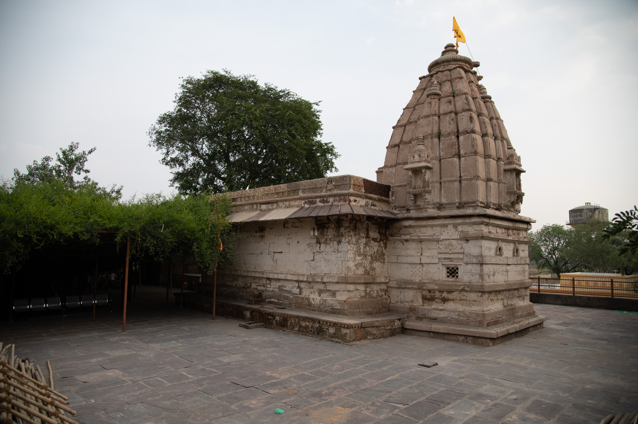 The main temple structure is visible from the southwest direction. The garbhagriha, unlike the mandapa exterior, shows some decoration on its façade. The garbhagriha stands on base mouldings with jaali (checkered) windows and chaitya arches. It has a simple latina-type shikhara (spire) with niches topped by udgama pediments (pediments with interconnected chaitya dormers), which look like miniature shikaras. Bijapuraka (citron fruit) sits atop an amalaka at the apex.