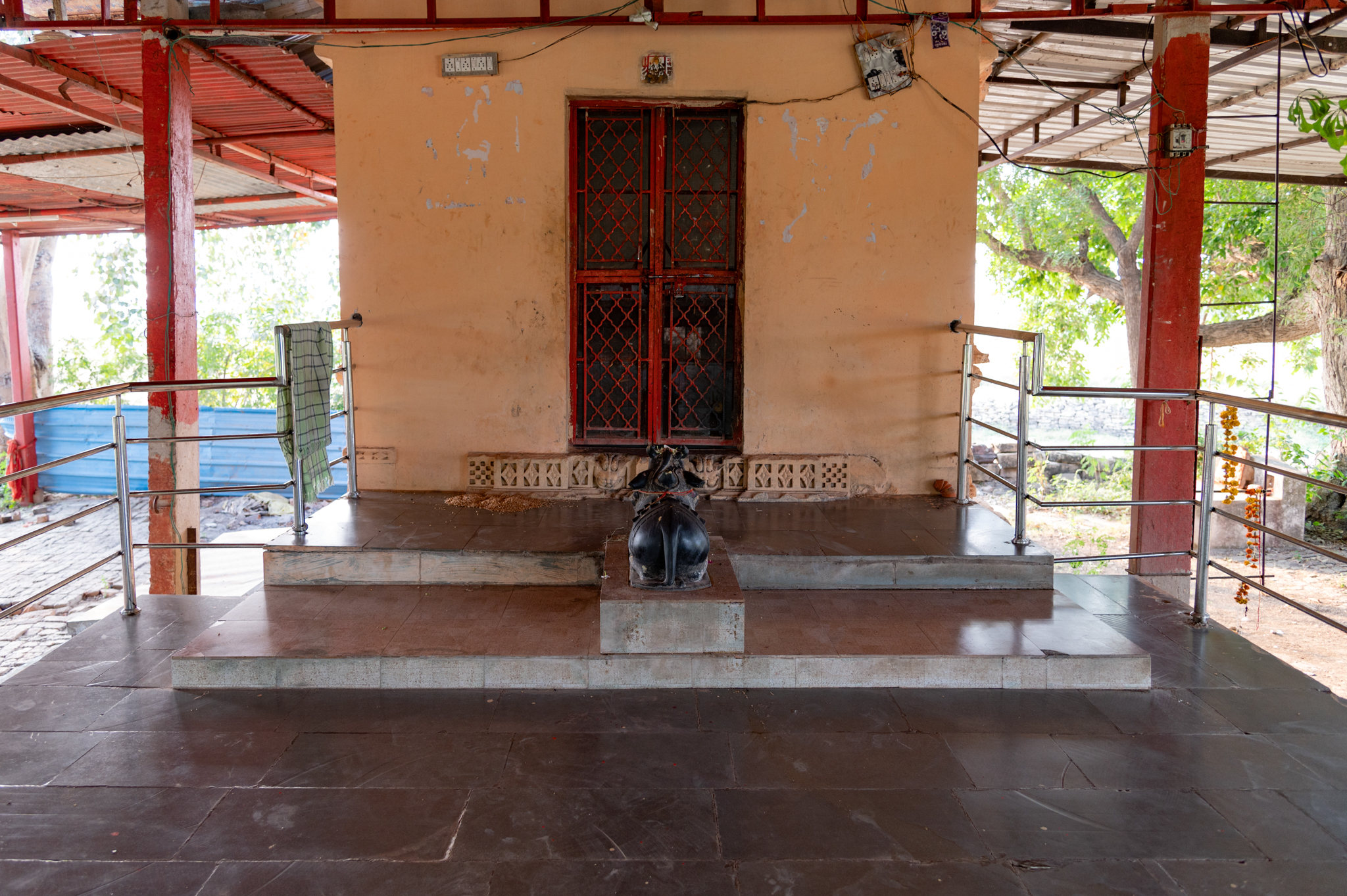 The temple's mandapa is open and contains only base mouldings from the old structure. It now has a smooth tile floor, and there are two broad stairs at the end that lead to the main sanctum. On one of the stairs stands a black stone figure of Nandi facing the sanctum. The front wall of the main sanctum is also a new structure with a metal gate to enter. The udumbar (threshold) of the sanctum houses the original part of the temple, which is now the only remaining decorative element of the entire façade.