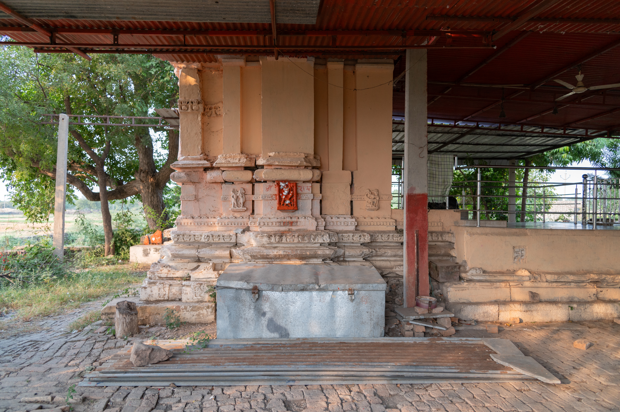 The garbhagriha, currently in its elevation, consists of the original vedibandha and jangha. The vedibandha is made up of various mouldings, while the jangha has a bhadra (central offset) and karna (corner projections). The image shows that the jangha on the temple's right lacks any sculpture on the bhadra niche, while the other two sides feature deity figures.