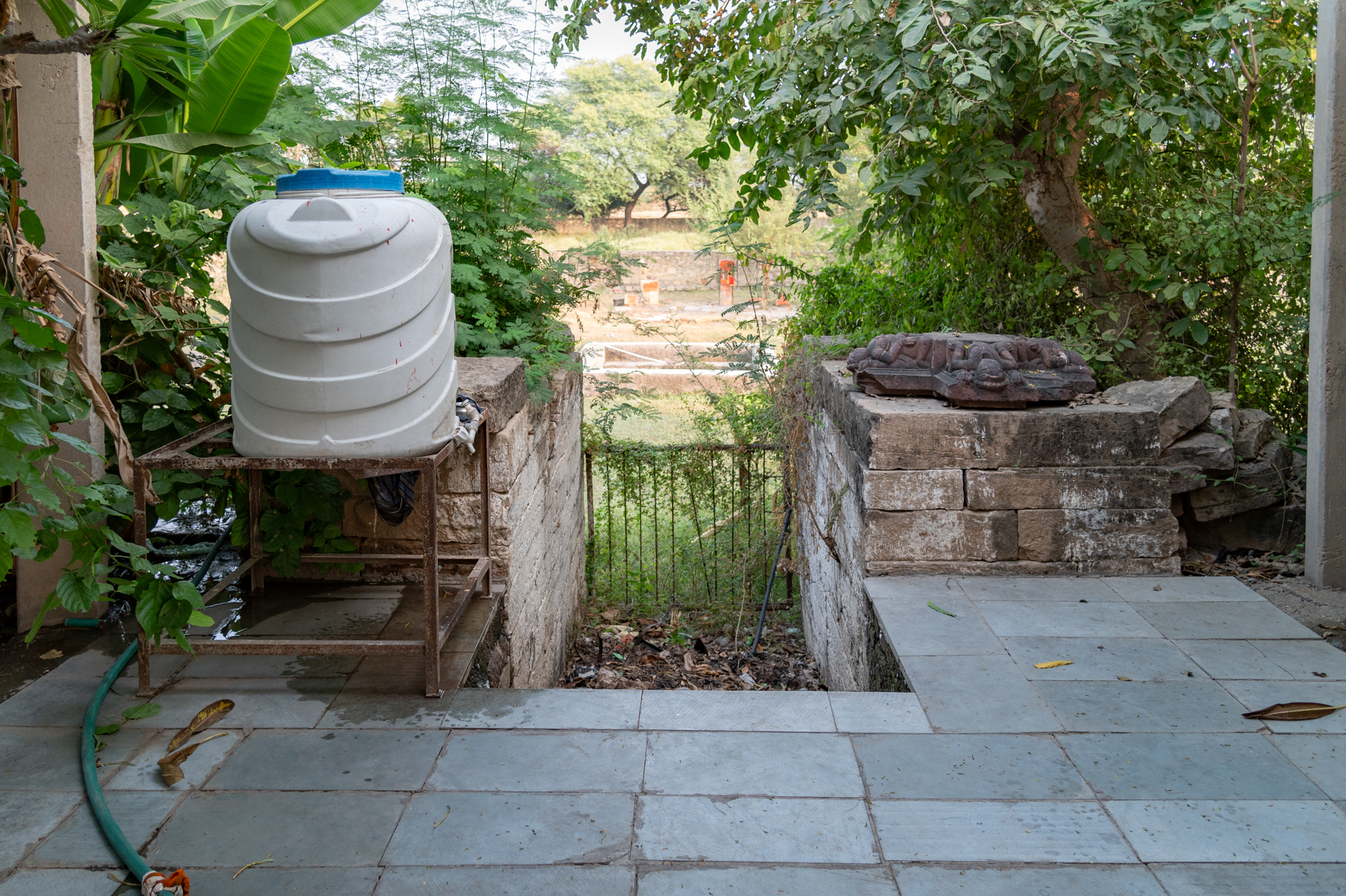 The front entrance (towards the west), possibly the original entry point in earlier times, is now locked with a metal gate, which seems to have not been in regular use. There is a flight of steps that leads to the temple complex. Currently, a water tank sits on one side of the entrance to cater to the temple's and devotees' needs, while a broken fragment of a pillar bracket occupies the other side.