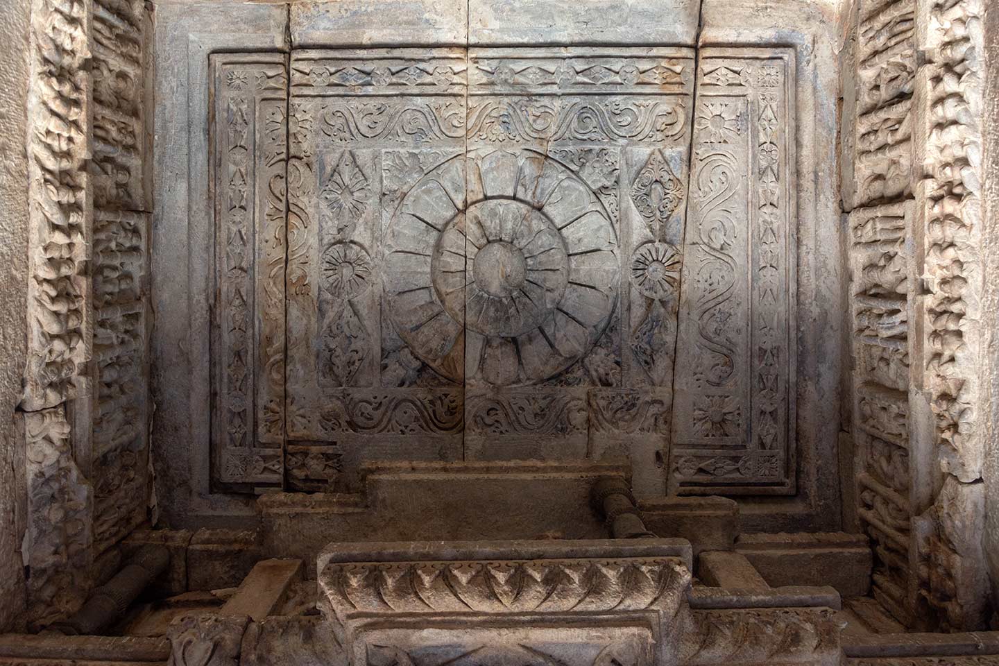 This is the flat square ceiling in the aisles of the mandapa (pillared hall). The ceiling features a large lotus medallion, encircled by floral patterns. The beams below the flat ceiling have friezes with a variety of human figures.