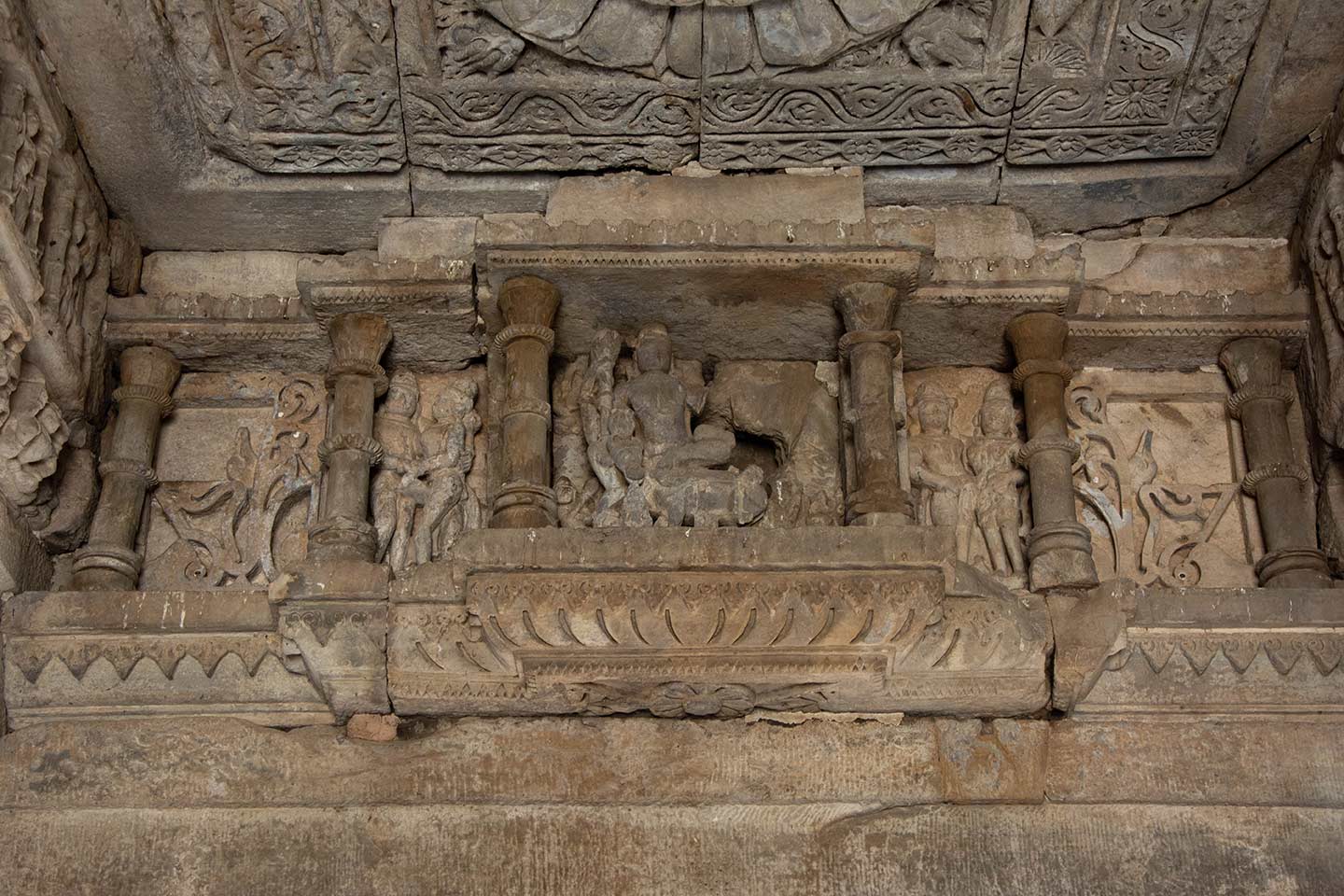 There are sculptures in deep niches just below the flat ceilings of the mandapa's aisles (pillared hall). The sculpture depicts Shiva and Parvati on Nandi, with the sculpture of Parvati shattered. Two attendants flank the main sculpture. There is a second niche beyond the attendants, which has a gavaksha (dormer window) motif.