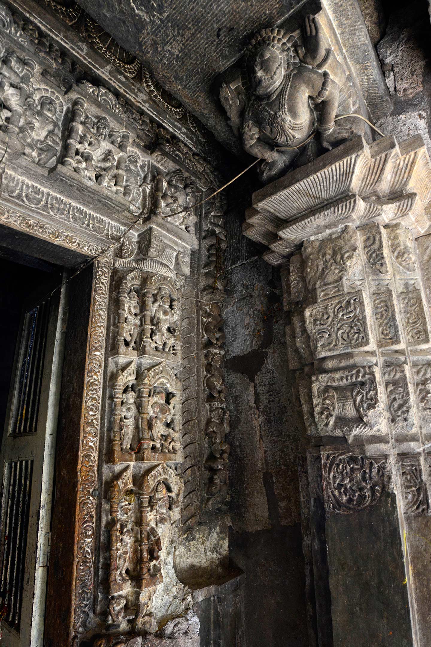 The dvarashakha (door jamb) of the central garbhagriha (sanctum sanctorum) in the Neelkanth Mahadev Temple is ornate. Seen here are details of the antarala (vestibule or antechamber) pilasters and the right side of the dvarashakha, which has one main shakha (vertical band) with deities on it. The pilasters of the antarala have on their capitals bearded bharavahakas (load bearers).