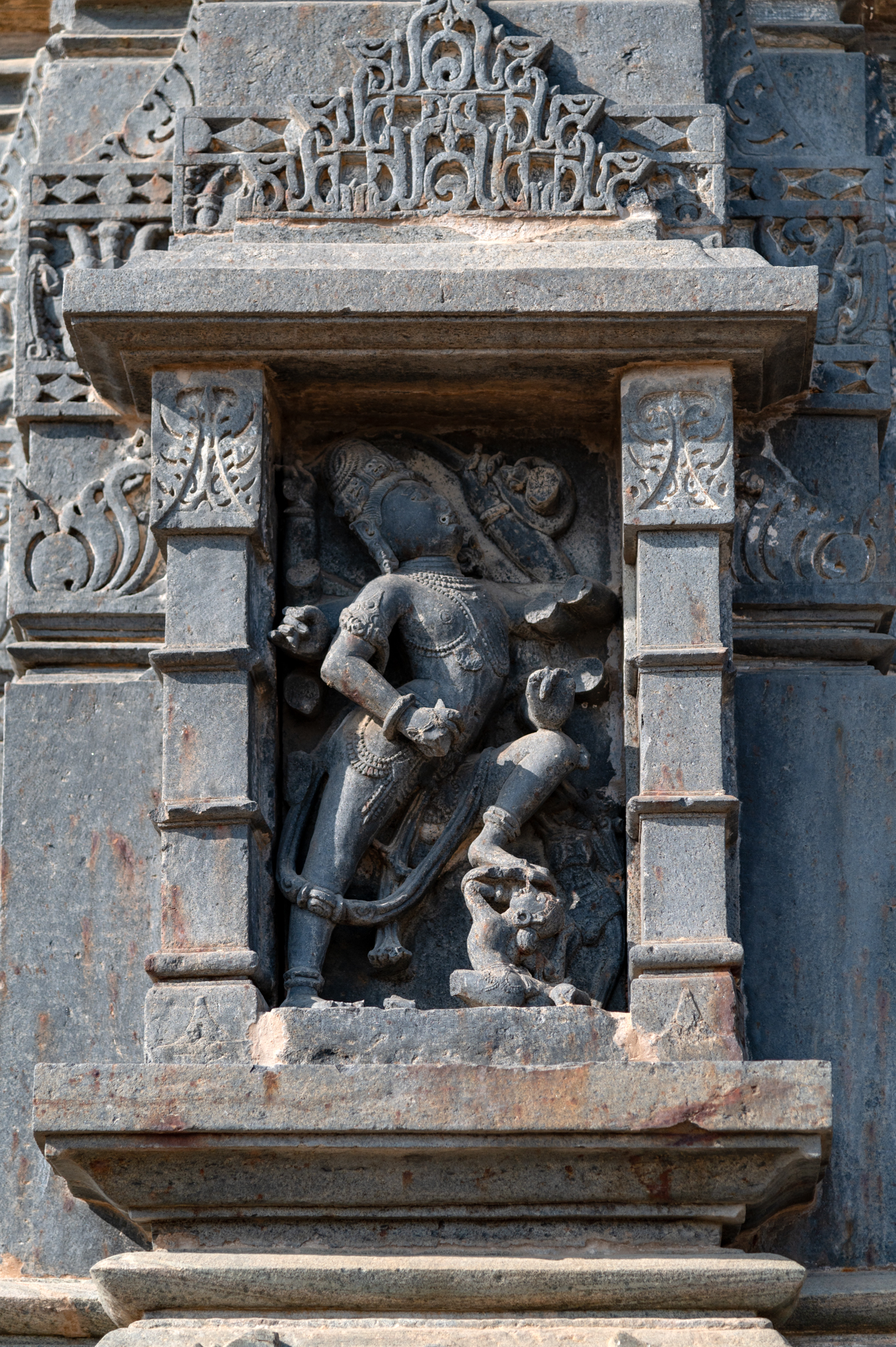 The Mandaleshwar Mahadev Temple's south-facing central projection features an icon of Tripurantaka Shiva. Despite losing several attributes, the icon depicts the six-handed deity attacking a demon with his foot. The jata mukuta (matted hairdo) is peculiar.