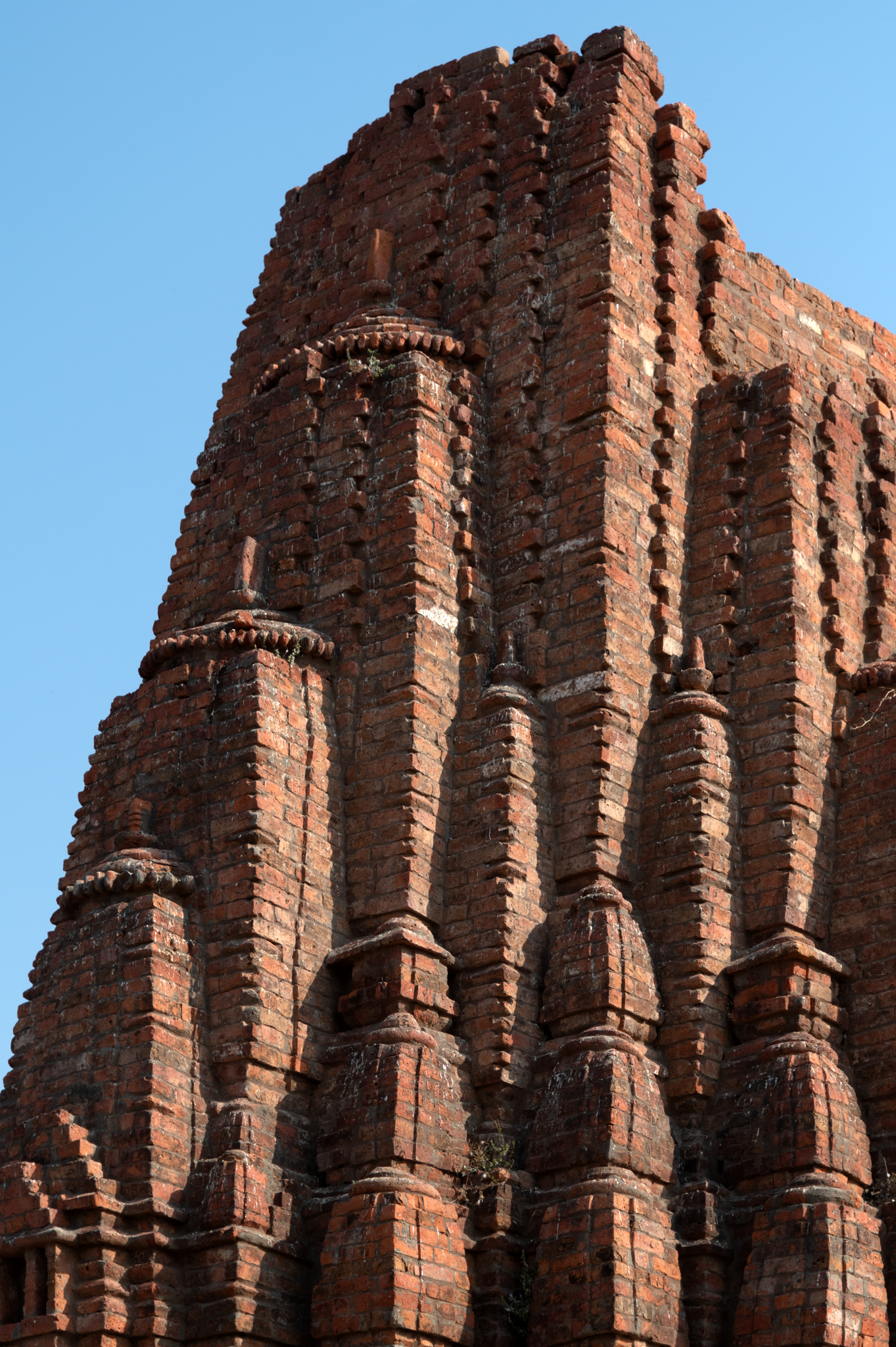 The Mandaleshwar Mahadev Temple constructs its shikhara (superstructure) from brick. The shekhari (multi-spire) variety of Latina shikhara features numerous small shringas (spires) that complement the mulashringa (main spire). These half and miniature shringas provide a cascading effect to the shikhara. The mulashringa mimics the style of a Latina sikhara. The mulashringa consists of five bands, with a broad central band and two bands on each side. These side bands are of equal size. The brick shikhara is likely a later addition to the temple.