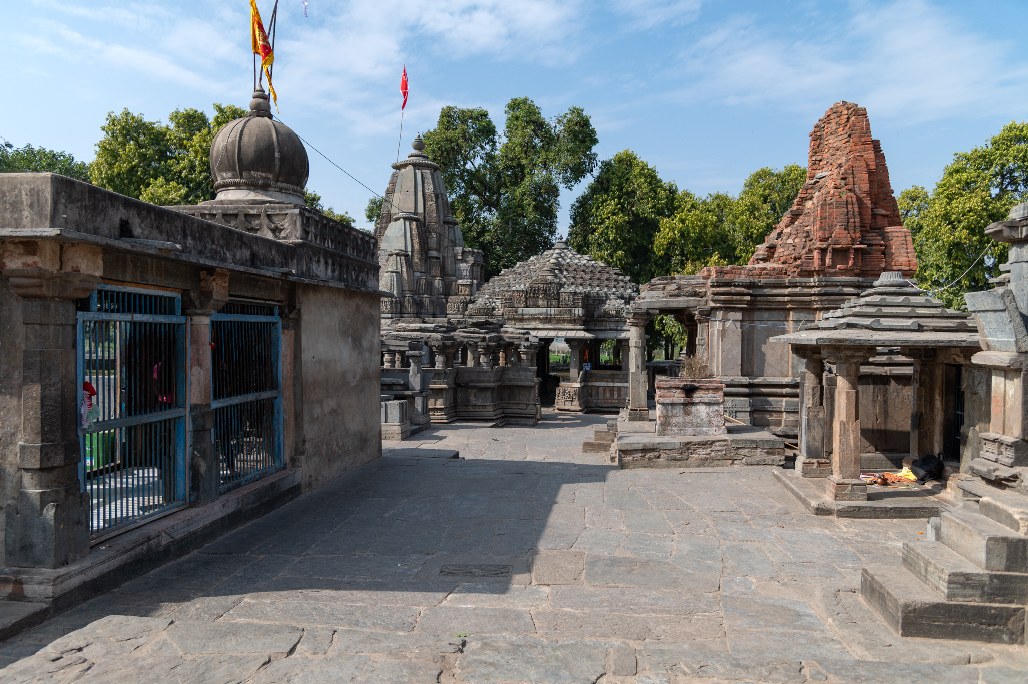 All of the extant structures from the Hanuman Garhi temple complex can be seen here. Starting from the left, one can see the gateway that must have been the original entrance of this temple complex, followed by several small shrines. The seventh shrine, seen towards the center, has a brick shikhara (superstructure), likely added at a later date than the original construction. Three important structures from the complex follow: a ruined Shiva Temple, a Devi Temple, locally known as Chaunsath Yogini Temple, and the Neelkanth Mahadev Temple. The kunda (water tank) is located in the foreground of all of these structures. The Neelkanth Mahadev Temple is the largest in this complex. Lakulisha worship is likely to be the focus of this temple.