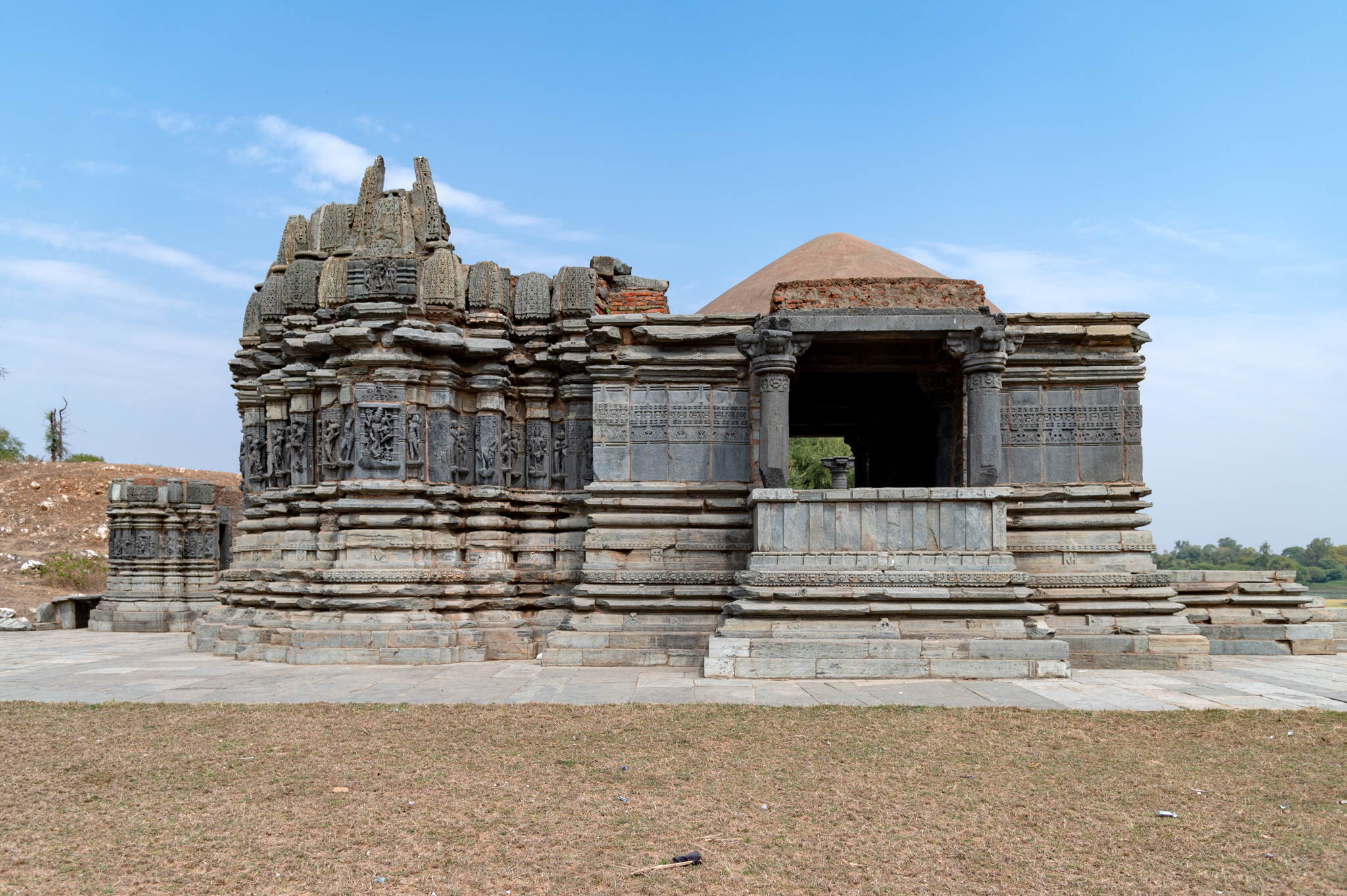 The central shrine consists of garbhagriha (sanctum sanctorum), antarala (vestibule or antechamber), and mukhamandapa (front porch). Only a partial portion of the shrine's shikhara (superstructure) remains intact. Icons and sculptures adorn the jangha (wall) of the garbhagriha, while geometric, floral patterns and kirtimukhas (faces of glory) adorn the mandapa. The temple's broken shikhara is a shekhari (multi-spire) variety. The shikharas' aedicules have gavaksha (dormer windows) designs on their surfaces.