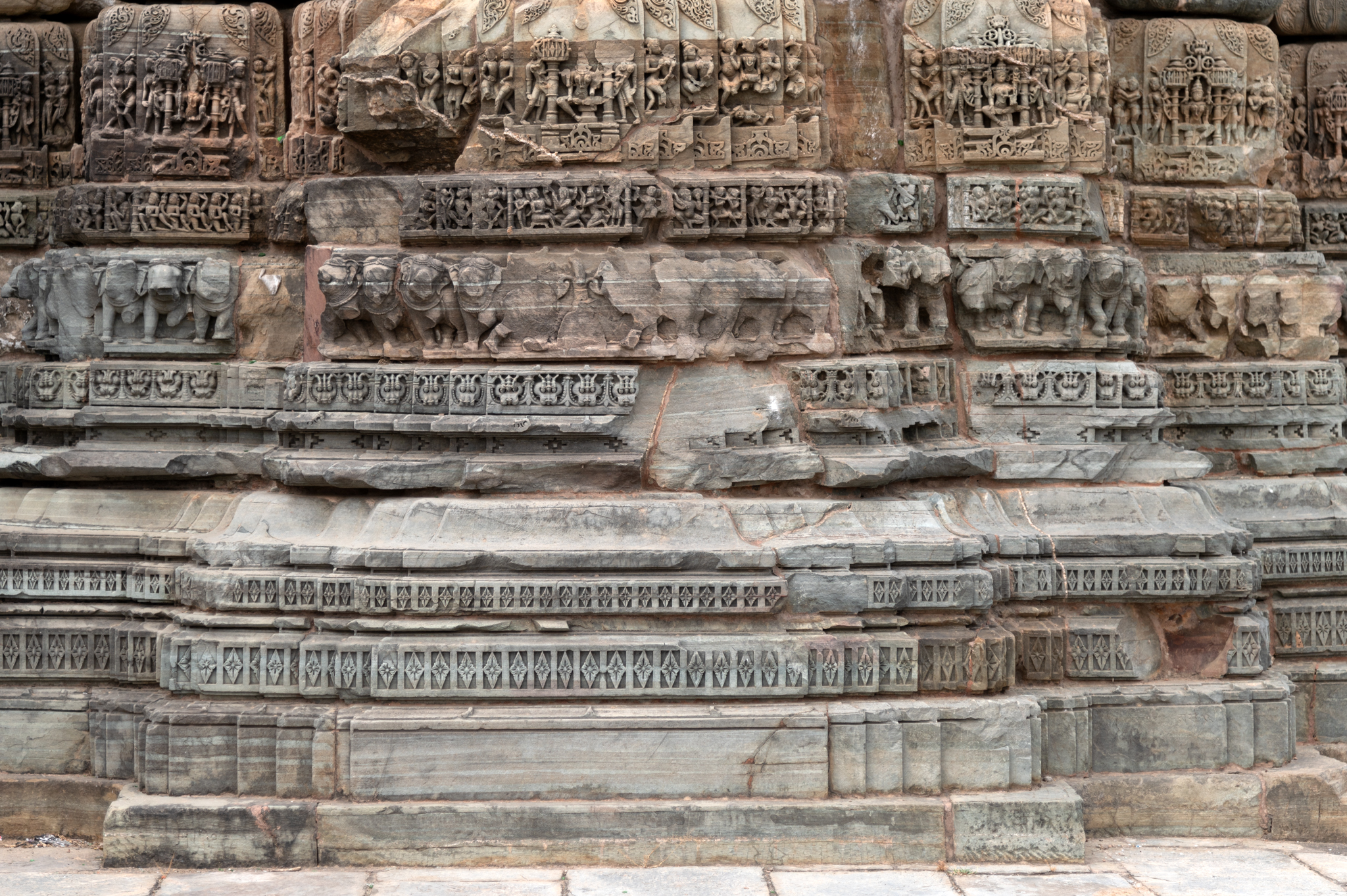 Closer view of the vedibandha (basal mouldings) of the Chaunsath Yogini Temple that are made up of a graaspatti (band of kirtimukhas or face of glory), gajathara (a band of elephants), narathara (a band of human figures), narathara, kumbha (pot) moulding, kalasaha (a pitcher), and kapotali (cyma recta). The most ornate moulding in the entire plinth is the kumbha, which has one central deity, usually a depiction of a goddess, flanked by mithuna (amorous couples) figures or ascetics.