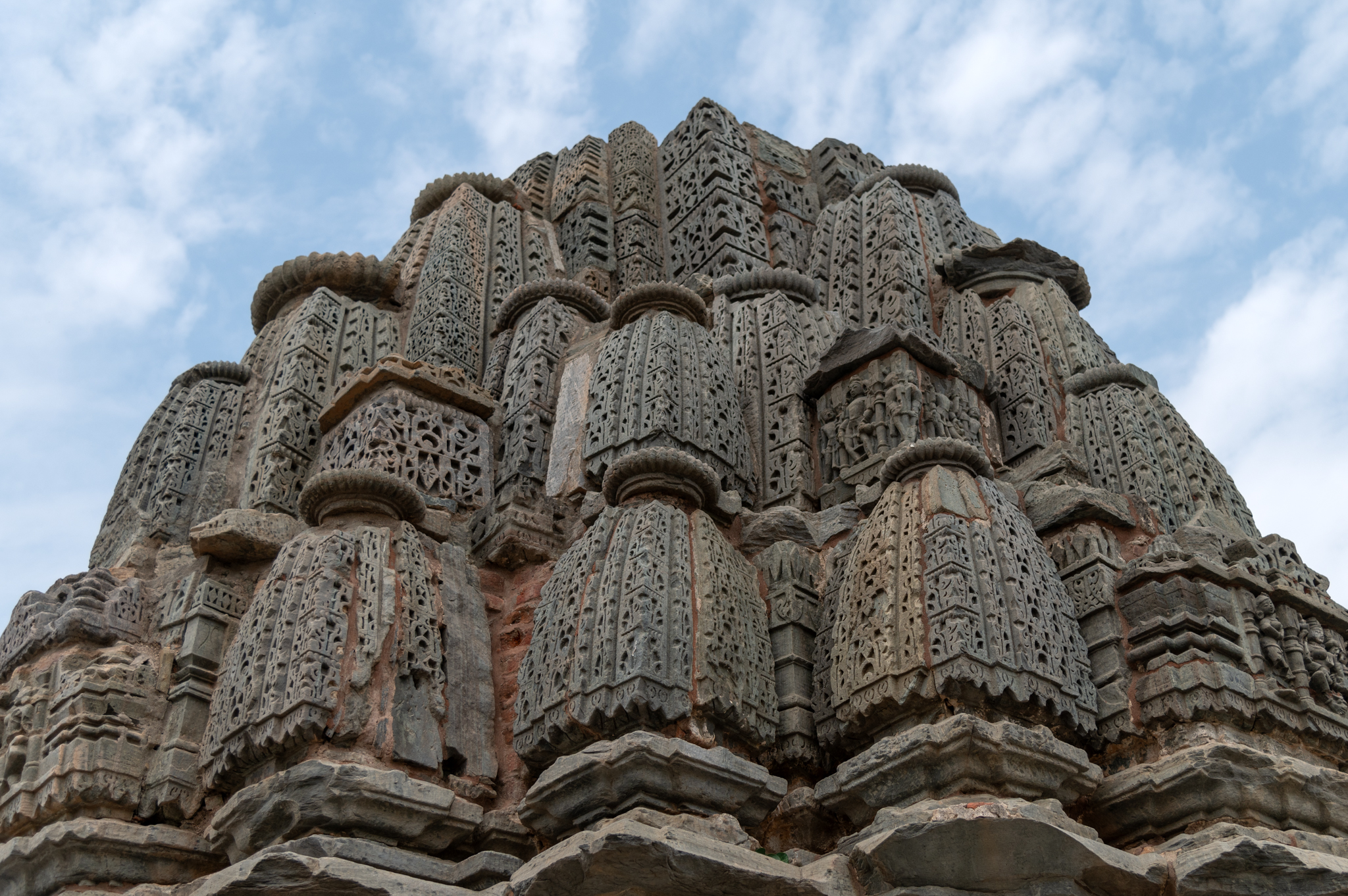 Cascading down a central mulashringa (main spire), there are several small miniatures of shikharas (spires), also sometimes called shikharikas, all of which together form the multi-spired shekhari shikhara. Each elevation's bottom features a depiction of Jain deities. The surface of the shikhara aedicules has intricate carvings made up of chaitya (dormers) mesh. Small ribbed discs, known as amalakas, top each aedicule, regardless of its size.