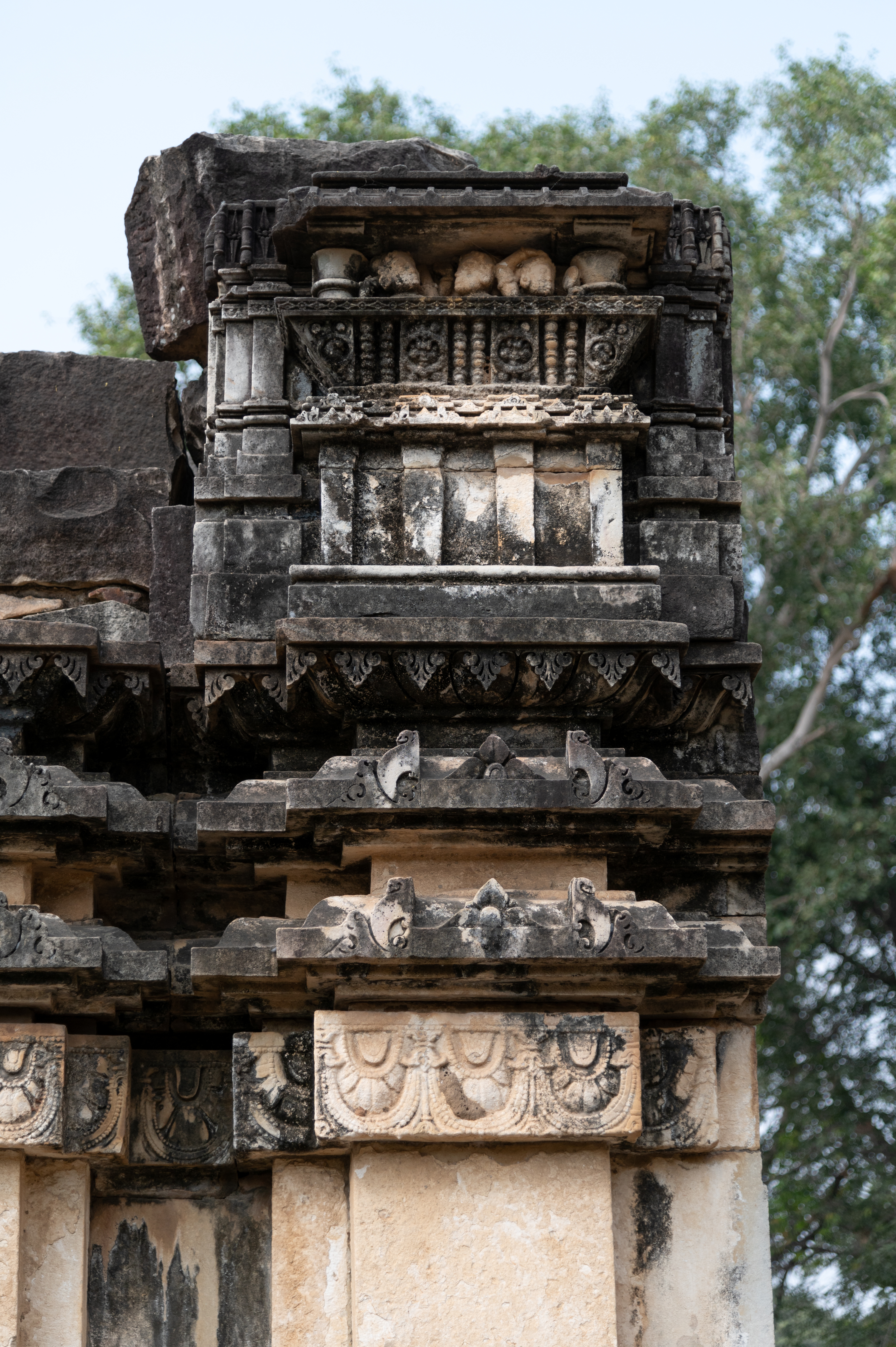 The shikhara (superstructure) of the Sheshashayi Vishnu Temple is in a dilapidated state. One part of it features a miniature balcony with three female figures. One of the female figures is shown holding a mirror and combing her hair.