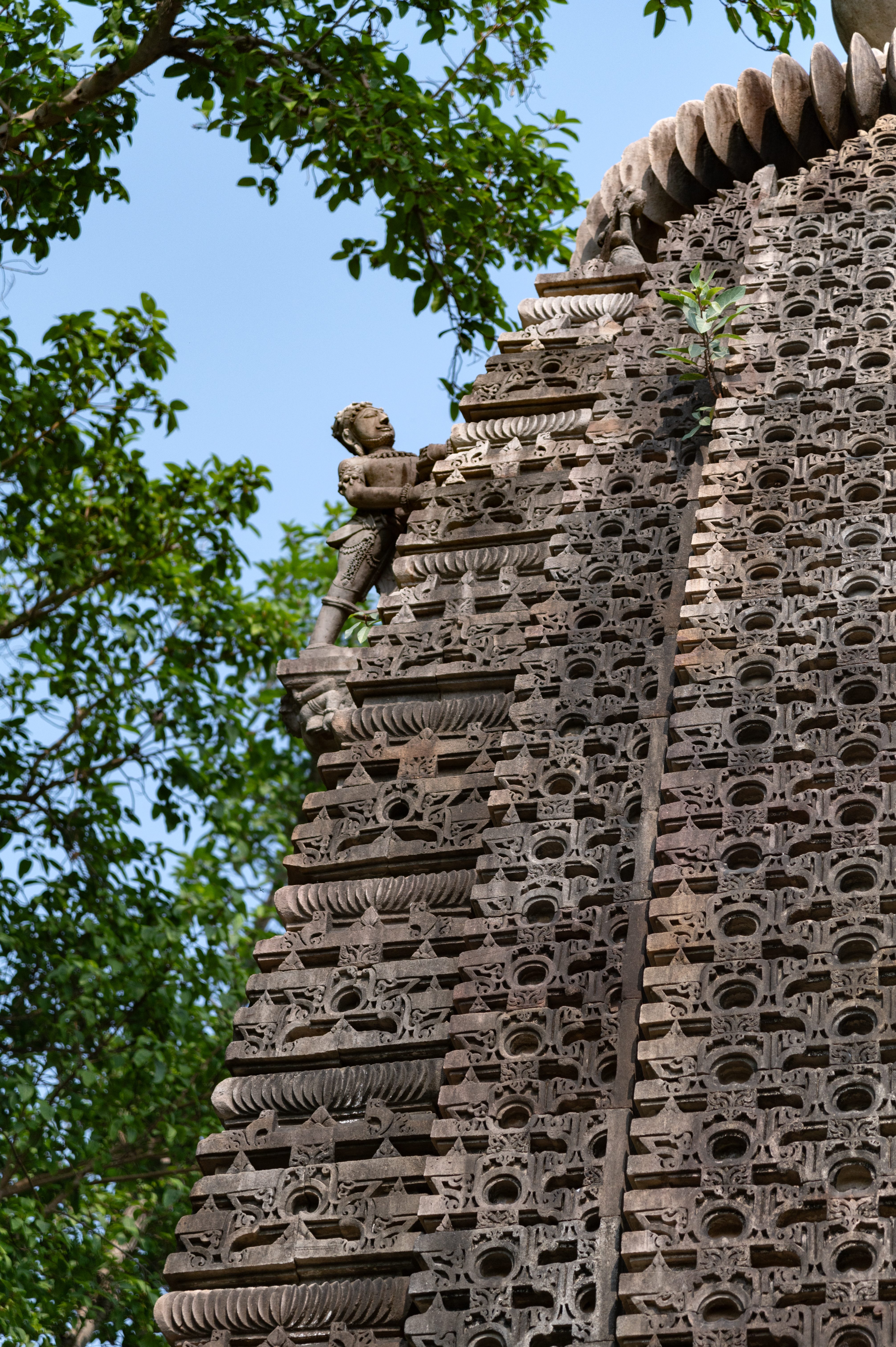 The shikhara (superstructure) of the garbhagriha (sanctum sanctorum) is carved in the latina (mono-spired) style with navabhumis (nine tiers). The shikhara is intricately carved with the jala of chaitya arches. A dhvajadharaka (flag bearer), a structure to hold the dhavja (flag), is also depicted at the top, on the rear side of the shikhara.