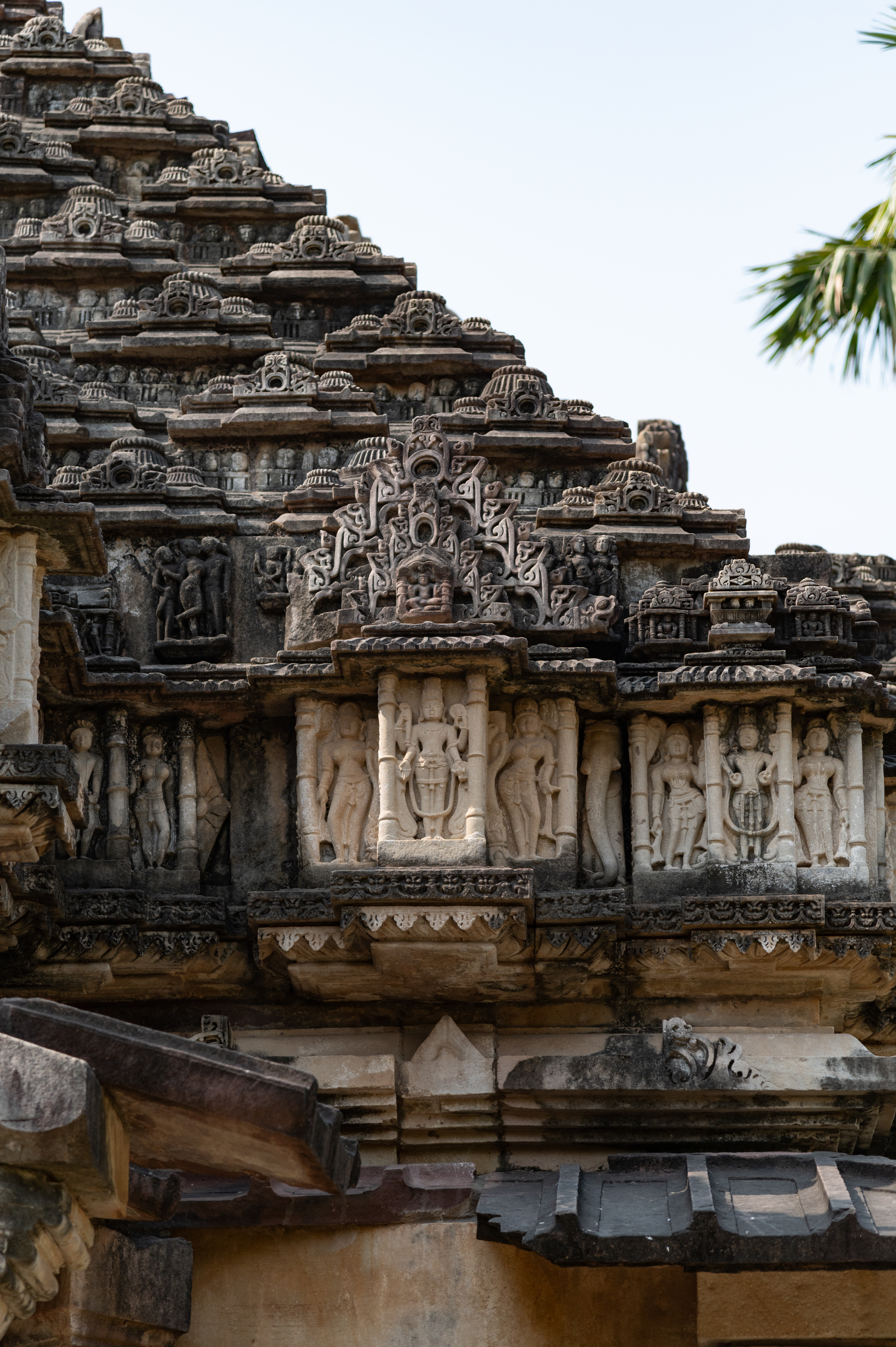 The pediment of the rangamandapa’s (open type of pillared hall) shikhara (superstructure) depicts other gods, including Surya and Vishnu. A standing figure of Surya and Vishnu can be seen on the pediment. A bejewelled Surya holds fully bloomed flowers in his two arms. The four-armed Vishnu is holding his respective weapons with one of his hands in varadahasta (boon-giving gesture) in which he holds an akshamala (rosary). Both deities are flanked by female figures.