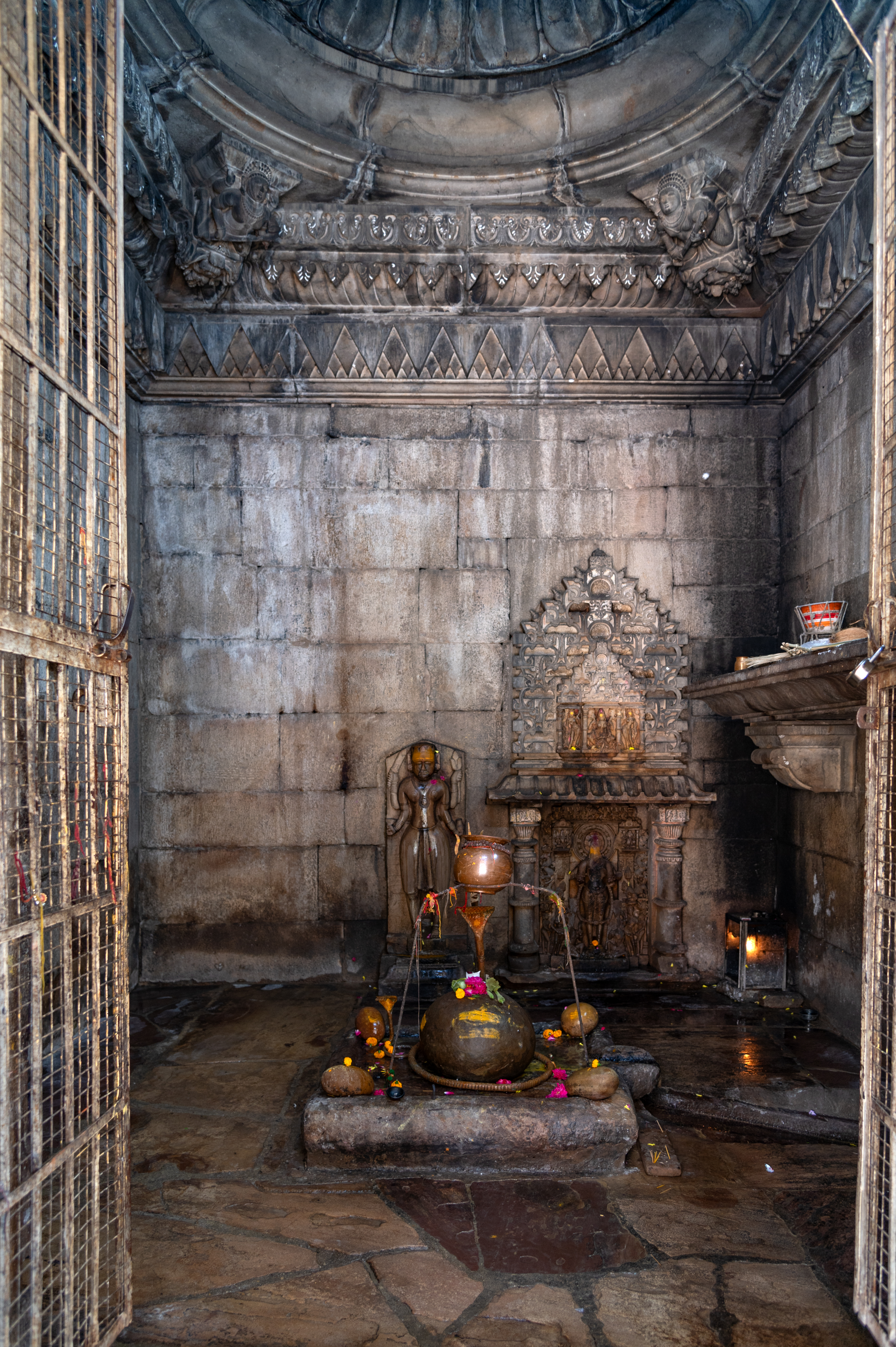 The garbhagriha (sanctum sanctorum), square in shape from the inside, features a distinct round or ghata (pot-shaped) linga, from which the temple derives its name, Ghateshvara. On the rear wall, a niche with an udgama (pediment of interconnected chaitya dormers) is fixed, housing a figure of a deity (currently without a head). Adjacent to it is another sculpture of a four-armed goddess. The sculpture of this goddess may belong to a later period, as her appearance differs from other sculptures in the temple.