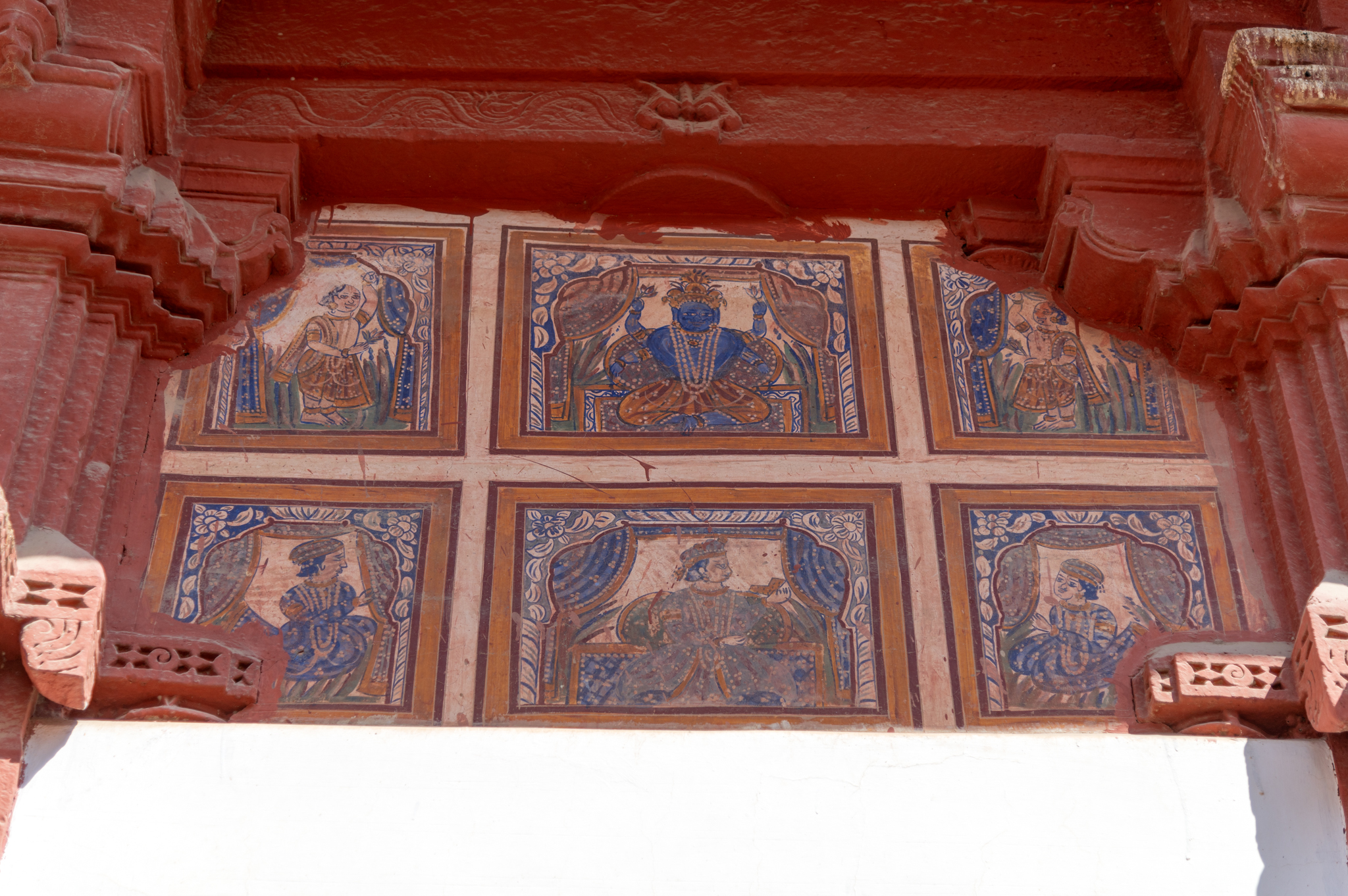 Paintings above the doorway in the exterior walls of the Bhandasar Temple. The horizontal block at the centre of the upper set also has a painting of Krishna in seating posture, flanked by gopis (female cowherd). Krishna is shown blue-skinned and holds two lotuses in the upper two hands.