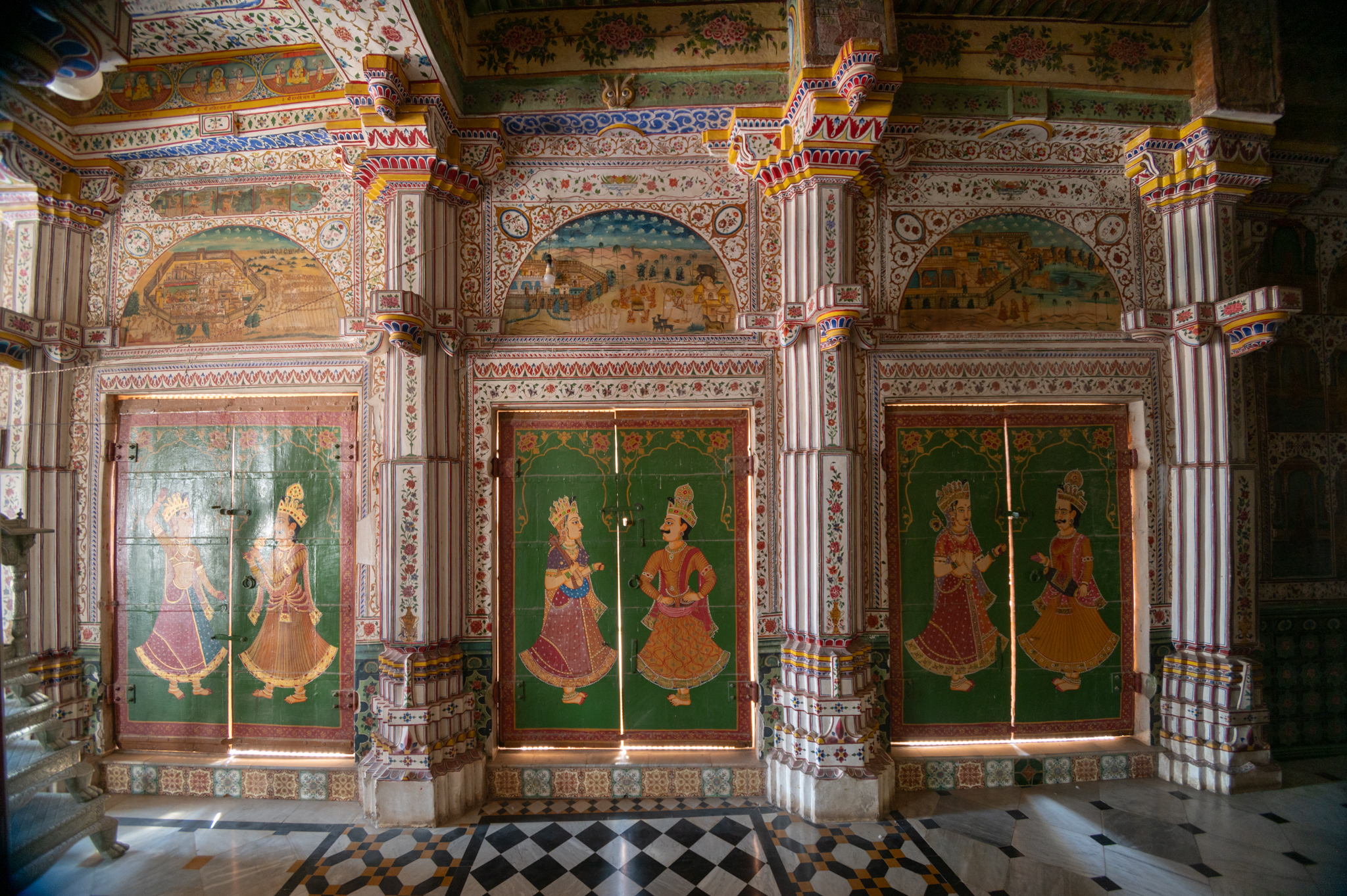 The doorways/long windows punctuating the walls of the mandapa (pillared hall) in the Bhandasar Temple are seen here. The wooden doors have paintings of musicians. The arch above the doorway has paintings of Tirthankara Rishabnatha’s life. A band above the arch depicts stories about forbidden things in Jain traditions.