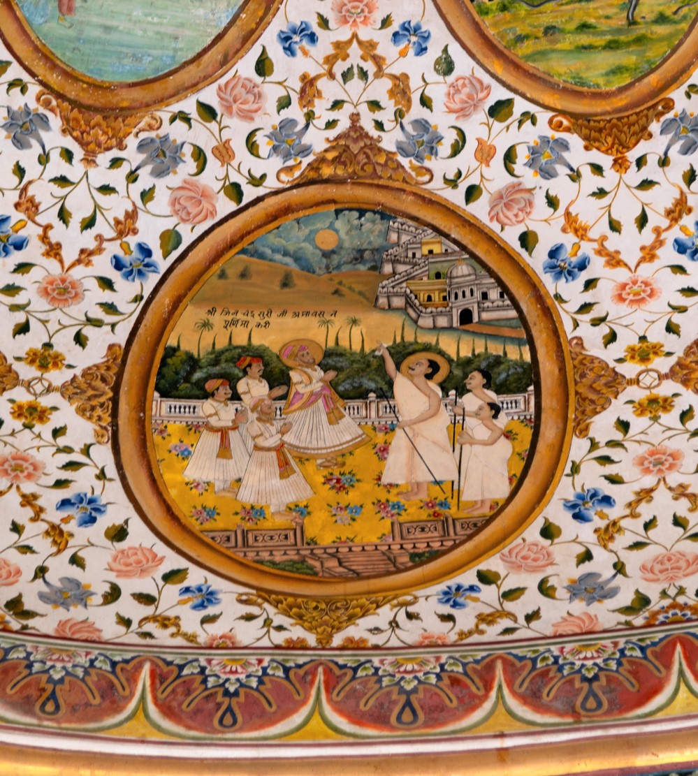 The third oval painting (in clockwise order) in the lower/outer circle in the ceiling of the mandapa (pillared hall) depicts an episode from Jinachandra Suri's life. Once, a disciple of Jinachandra Suri mistakenly told a Muslim religious leader it was a no-moon day when it was a new moon day. The Muslim leader spread the misinformation across the city, questioning the disciple’s knowledge of the day. To rectify the situation, Jinachandra Suri threw a gold plate into the sky, covering the moon and thus converting the day into a no-moon day. This miracle is supposed to have taken place in front of Emperor Akbar. The inscription reads, ‘Shri Jinachandra Suri ji na Purnima kari.’