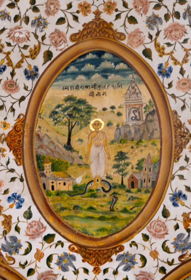 The painting in the inner/upper circle in the ceiling of the mandapa (pillared hall) likely depicts the story of Chandakaushika Nag and Mahavira. According to the tale, as Mahavira travelled through a forest, a snake named Chandak blocked his path. However, Mahavira, instead of being scared of him, stood at the place firmly. Chandak bit the Tirthankara, yet the latter remained calm, intending no harm to the snake. This story intends to teach everyone the importance of controlling anger and cultivating compassion. Mahavira has a divine halo behind his head, painted in golden colour. A temple dedicated to the snake is shown at the background of the painting. The inscription from this painting is not entirely legible, but it certainly includes the name of Mahavira Swami.