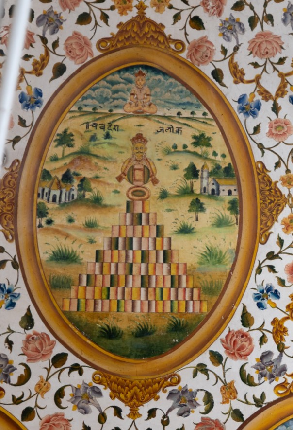  The painting in the inner/upper circle in the ceiling of the mandapa (pillared hall) represents Chaude Rajlok, a concept in Jain traditions and cosmology that signifies four celestial realms or heavenly abodes. These realms are regarded as higher spiritual dimensions in Jainism, representing stages of spiritual evolution and attainment of purity, leading to liberation from the cycle of birth and death. The painting has a pyramid with a Tirthankara positioned at its apex. The inscription reads, ‘Chaude Rajlok.’