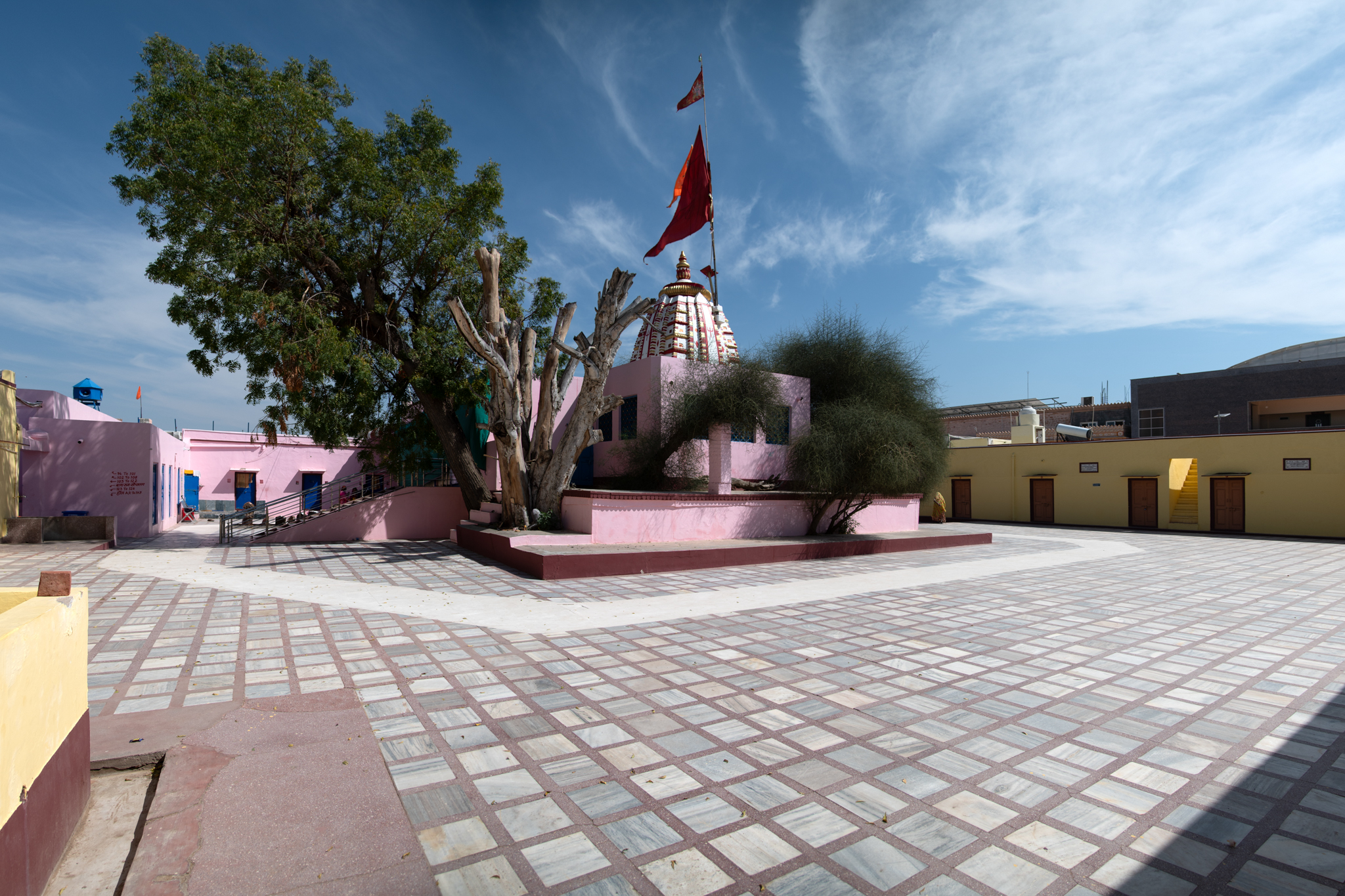 View of the Suswani Mata Temple from the north-western corner of the complex, in which the old shrine is centrally located and is surrounded by open spaces, with the rest house (dharamshala) constructed later. The sacred Kera tree and the latina shikhara (mono-spired north Indian variety of temple superstructure) are also visible in the picture.