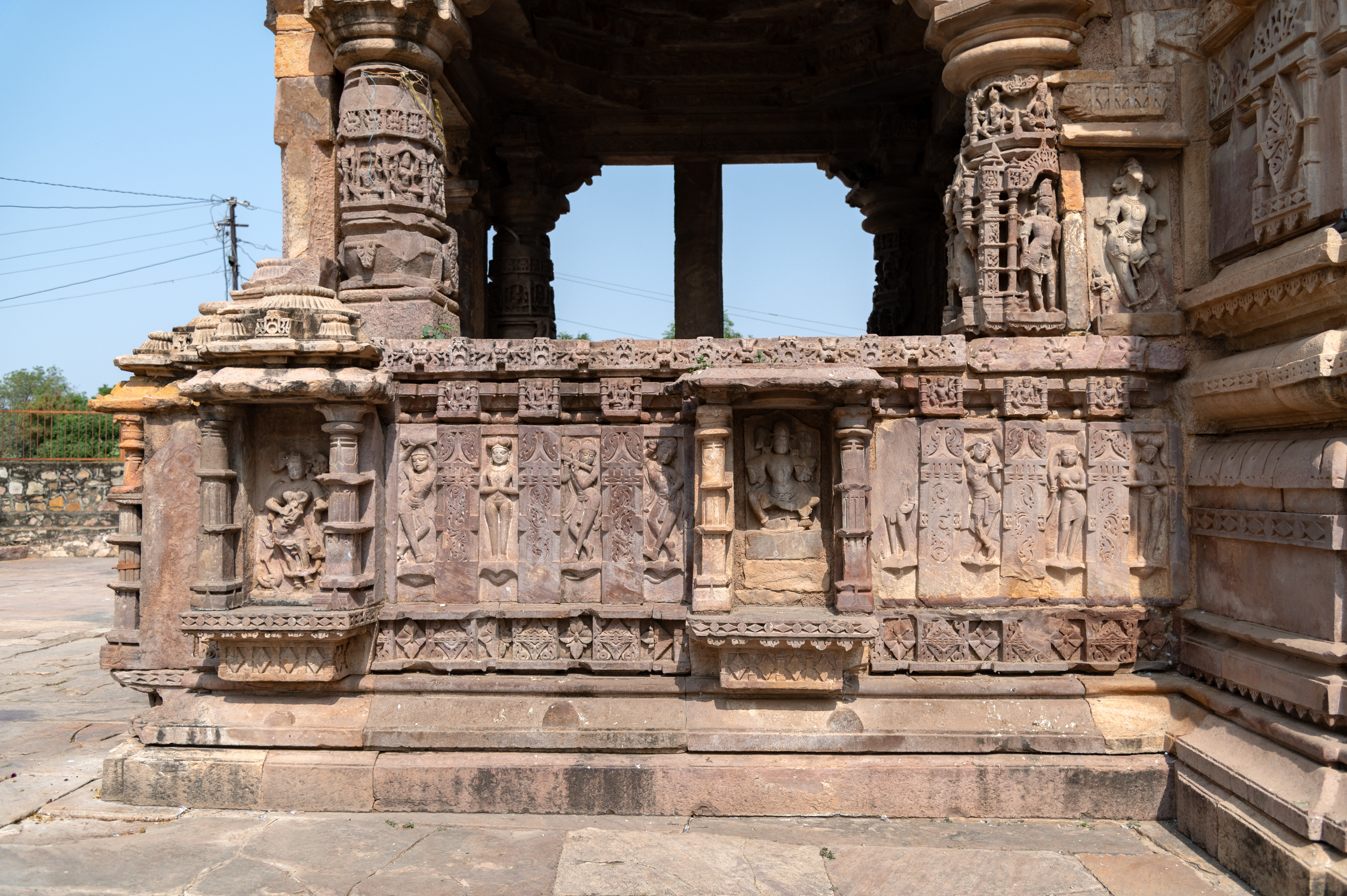The mukhamandapa (front porch) of the Mahakal Temple features a kakshasana (seat backs) adorned with niches housing divine figures, including deities like Brahma and Kaumari. Interwoven among these divine figures are depictions of ascetics, musicians, and surasundaris (celestial damsels).
