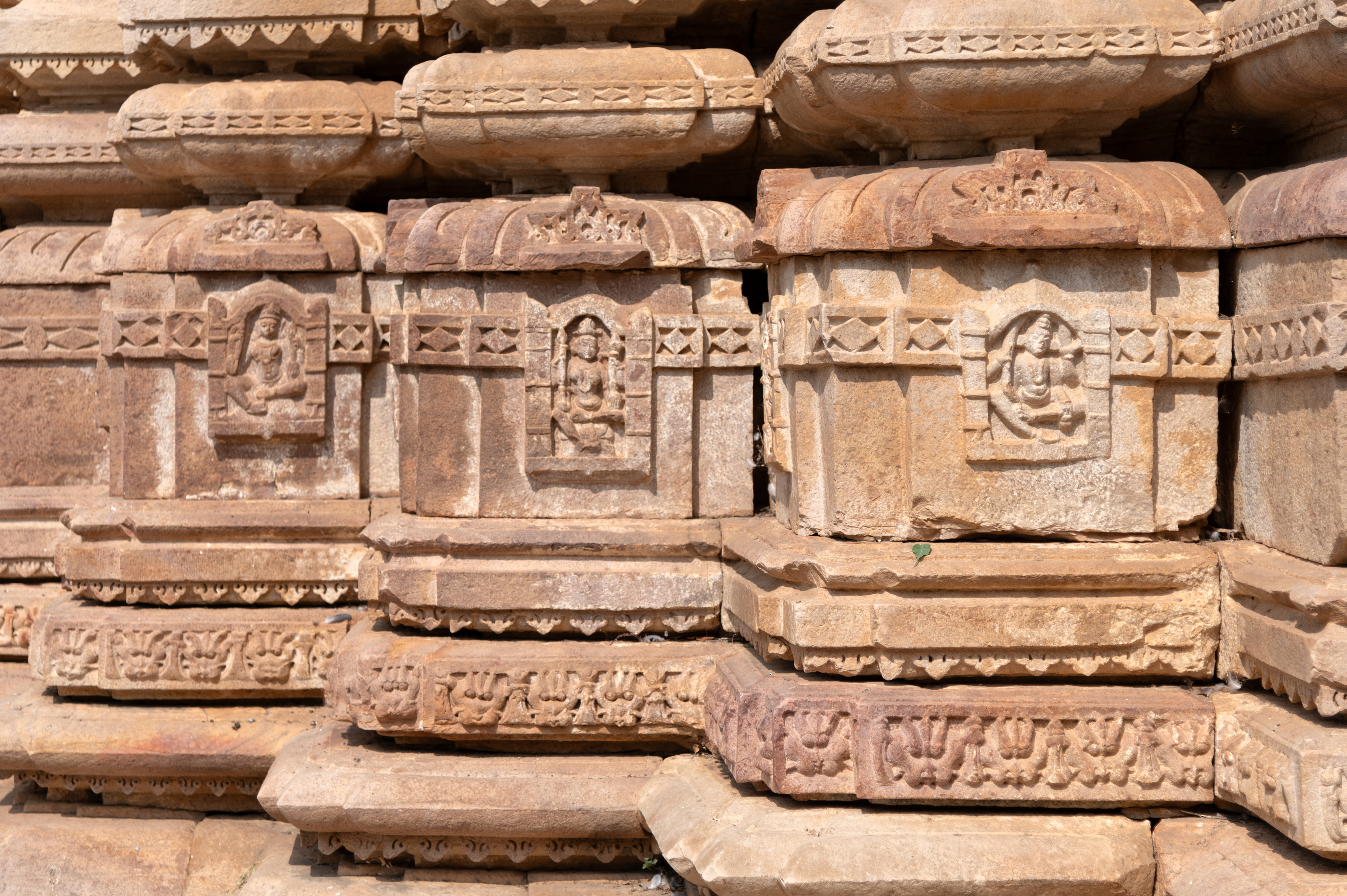 The kumbha (pot) moulding of the vedibandha (basal mouldings) stands out for the depiction of divine figures within the niches, featuring gods and goddesses like Kubera, the deity associated with wealth. Notably, the top of the kumbha is adorned with a chaitya arch, a feature commonly found on kapotapalika (cyma recta) mouldings. Below the kumbha is a band showcasing kirtimukha (face of glory) motifs, while above the kumbha, the moulding of kalasha (pitcher) is intricately carved with ratnapatta motifs.