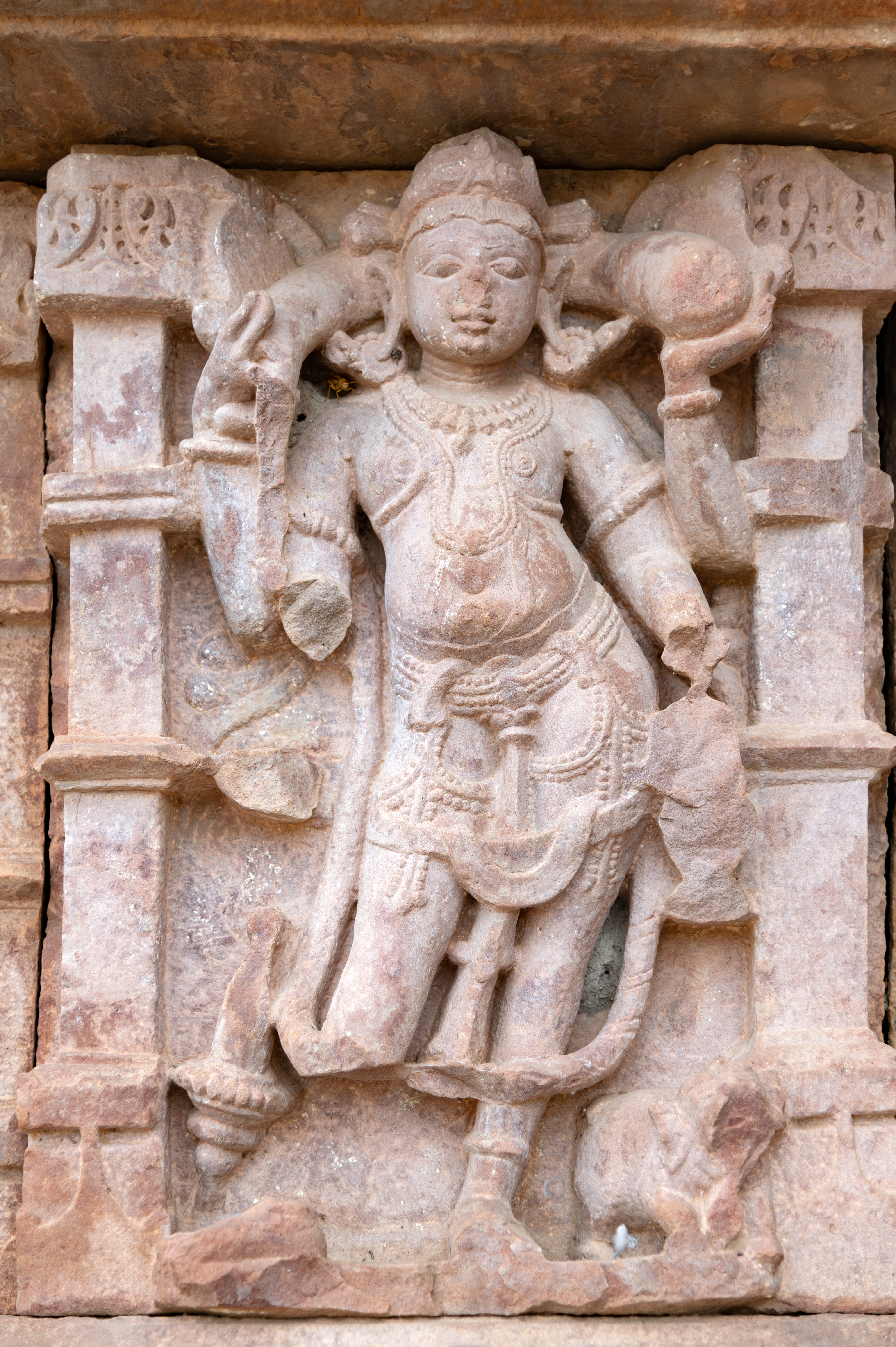 Kubera, accompanied by his elephant vehicle, is depicted with four arms on the kakshasana (seat back) wall of the Undeshwar Temple. He holds a money bag in his upper arms. Although his lower arms are damaged, it appears that he was initially holding a mace and a water pot in his lower right and left hand, respectively.