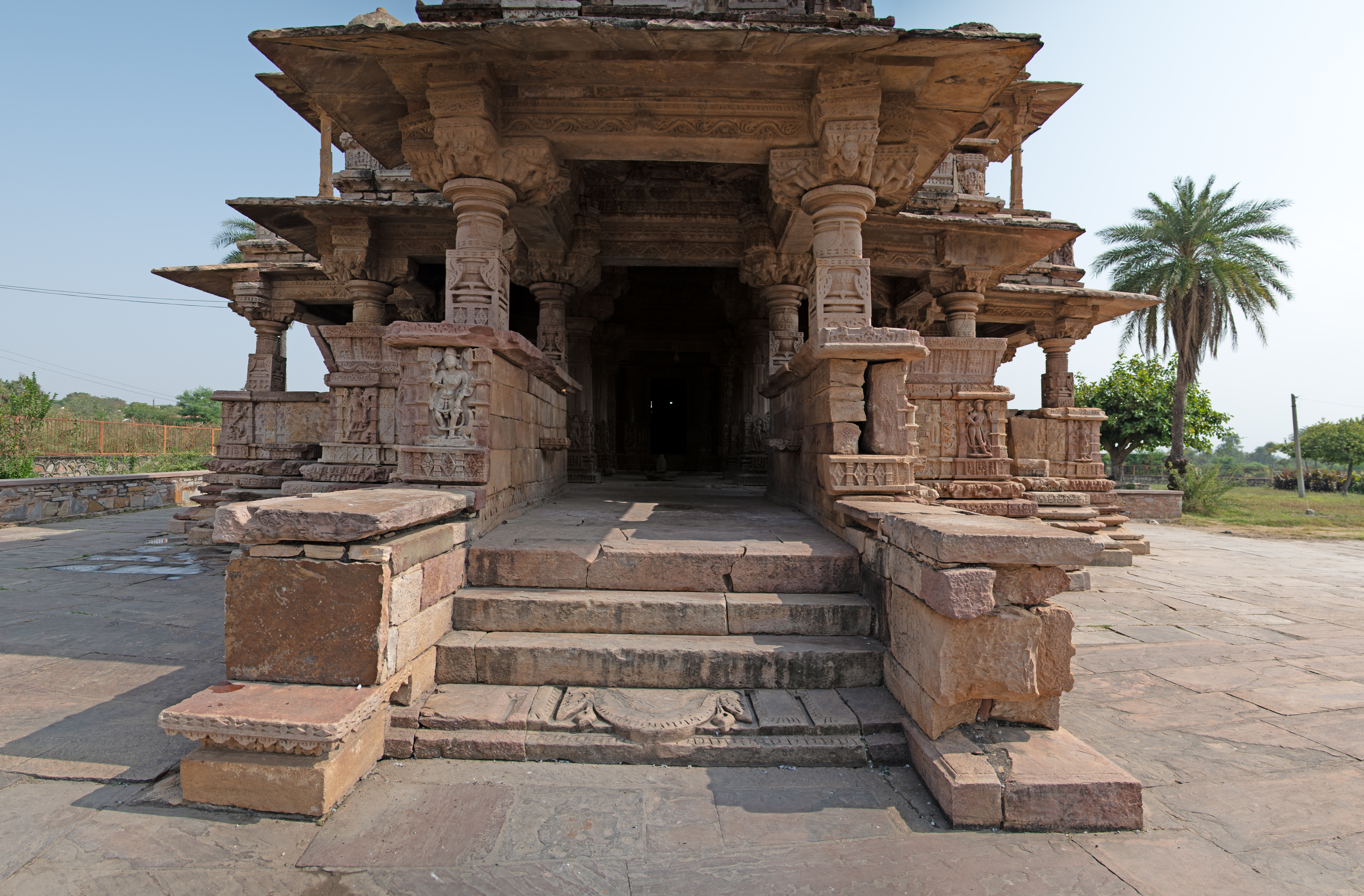 Access to the temple is through the mukhamandapa (front porch) of the Undeshwar Temple, with steps bordered by depictions of deities. The mukhamandapa is a small hall with low walls along its sides. Atop these walls, four pillars stand at each corner, supporting the flat roof above.