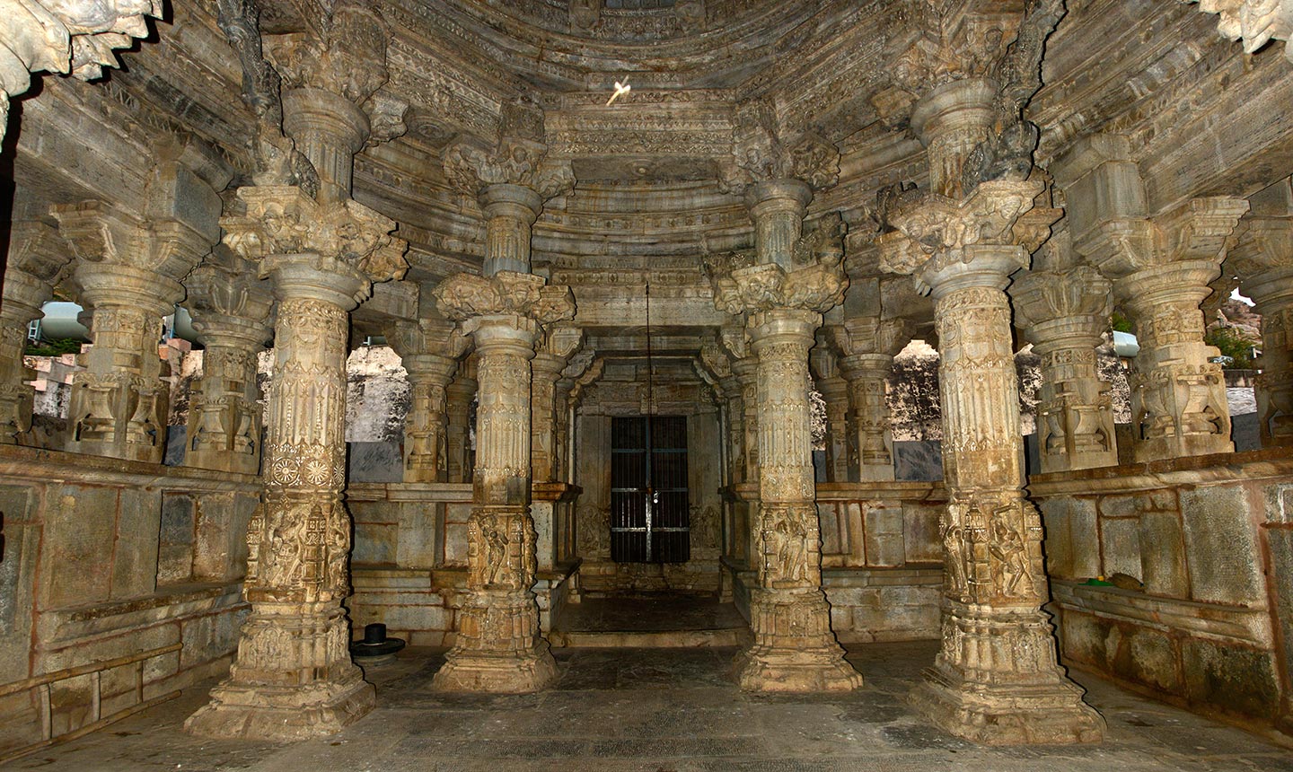 The ceiling of the mahamandapa (pillared hall) rests on eight elaborately carved tall pillars. Each pillar has a square base, transitioning into a shaft that changes from square to octagonal in the middle and finally becomes circular at the top. Above these are architectural mouldings, a shaft that supports the capital and carved bharvahakas (mythical flying load-bearing figures). Notably, the square portion of the shaft of each pillar in the mahamandapa is carved with a niche on each of its four faces. Within these niches are sculptures portraying various figures, including apsaras (celestial damsels), yogis (ascetic), or royal figures in acts of veneration and, in one case, a four-armed Bhairava.