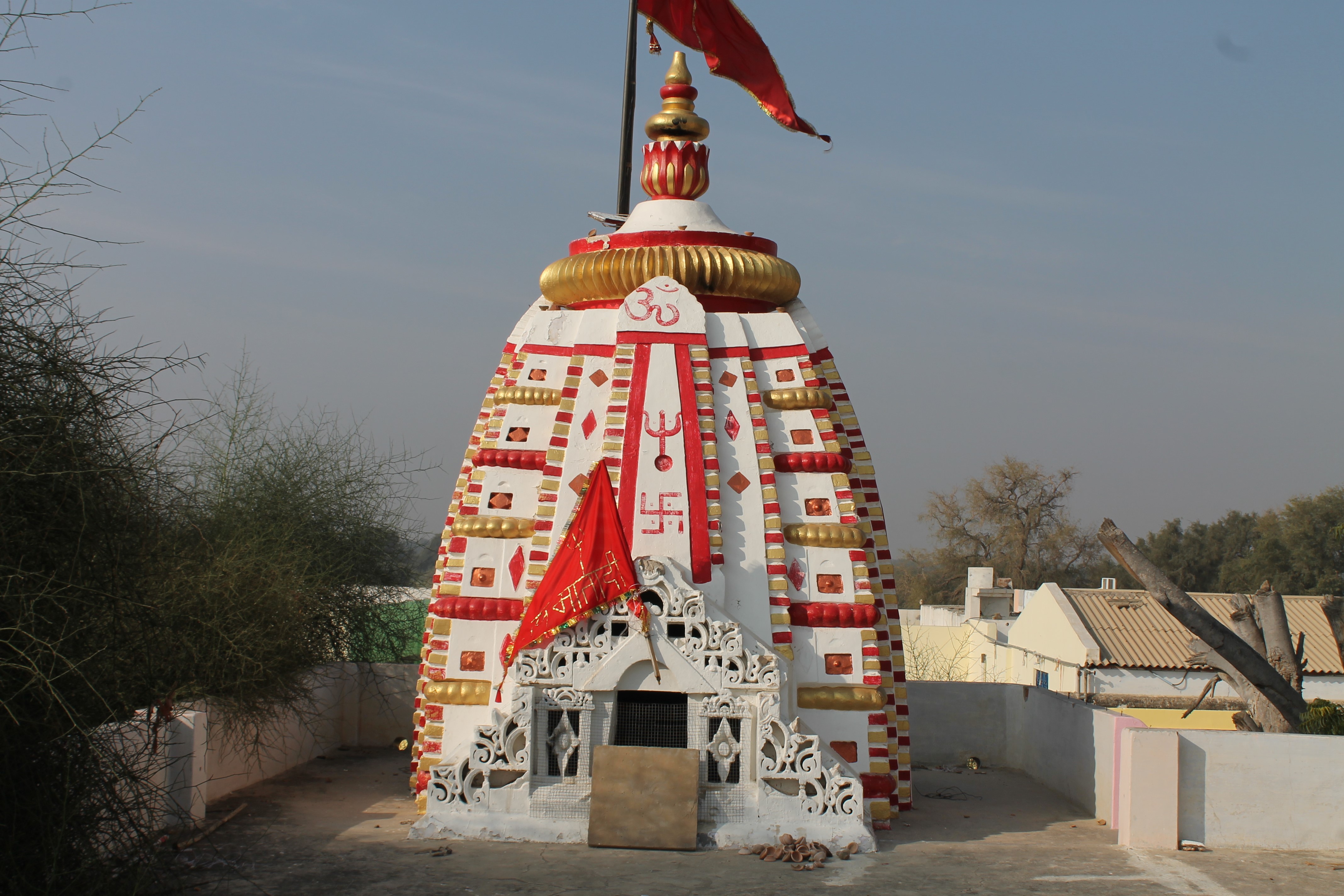 Seen here is the front side, east-facing, of the shikhara (superstructure) above the main Suswani Mata Temple, which is of a latina nagara (mon-spired) variety. Square on plan, the shikhara is composed of curvilinear bands. A vertical band of aedicules arranged in a descending manner from top to bottom on the corners. The central band is plain.