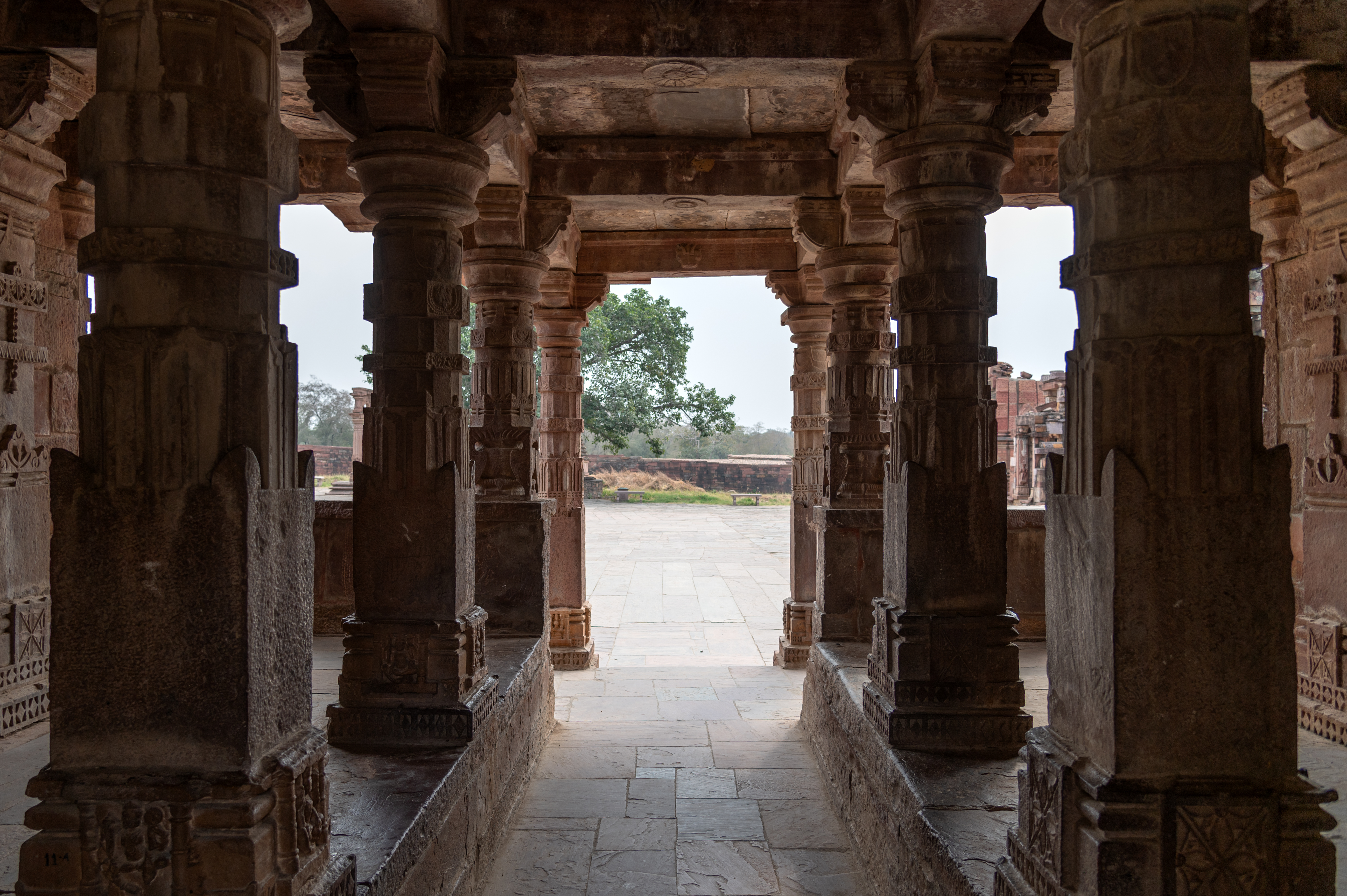 This is a view of the interiors of the semi-open pratoli of the Mahanaleshwar temple complex. Verandahs with square-shafted ruchaka pillars flank the central passage on both sides. The pillar bases are carved with divine figures.