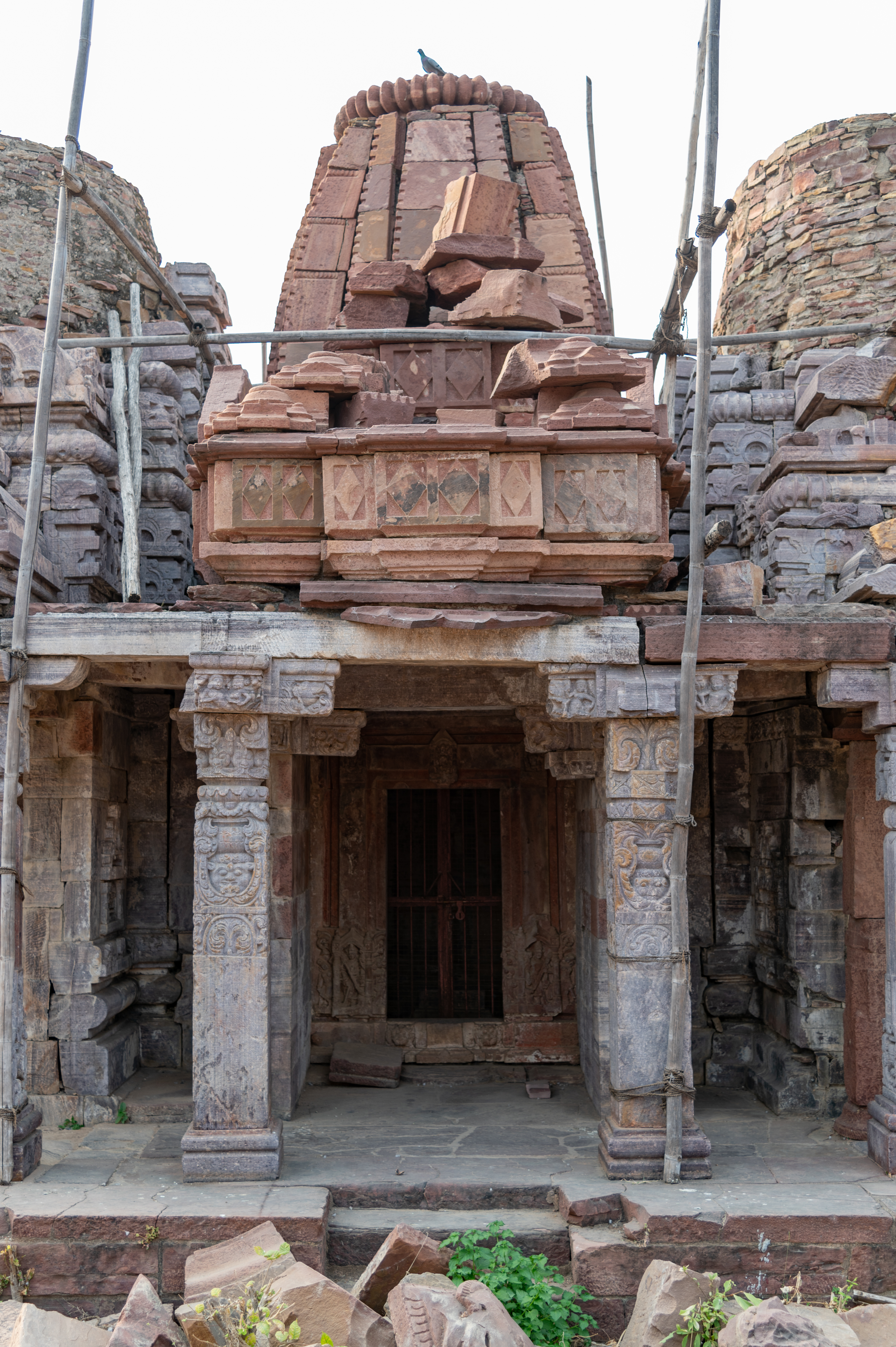 The central shrine in the Triple Shrine Temple shares the porch with its adjacent shrines. The central shrine's construction differs from the other two shrines. The shikhara (superstructure) of the mandapa (pillared hall) has collapsed. Only the basal mouldings, made up of three stone blocks with diamond motifs, have survived.