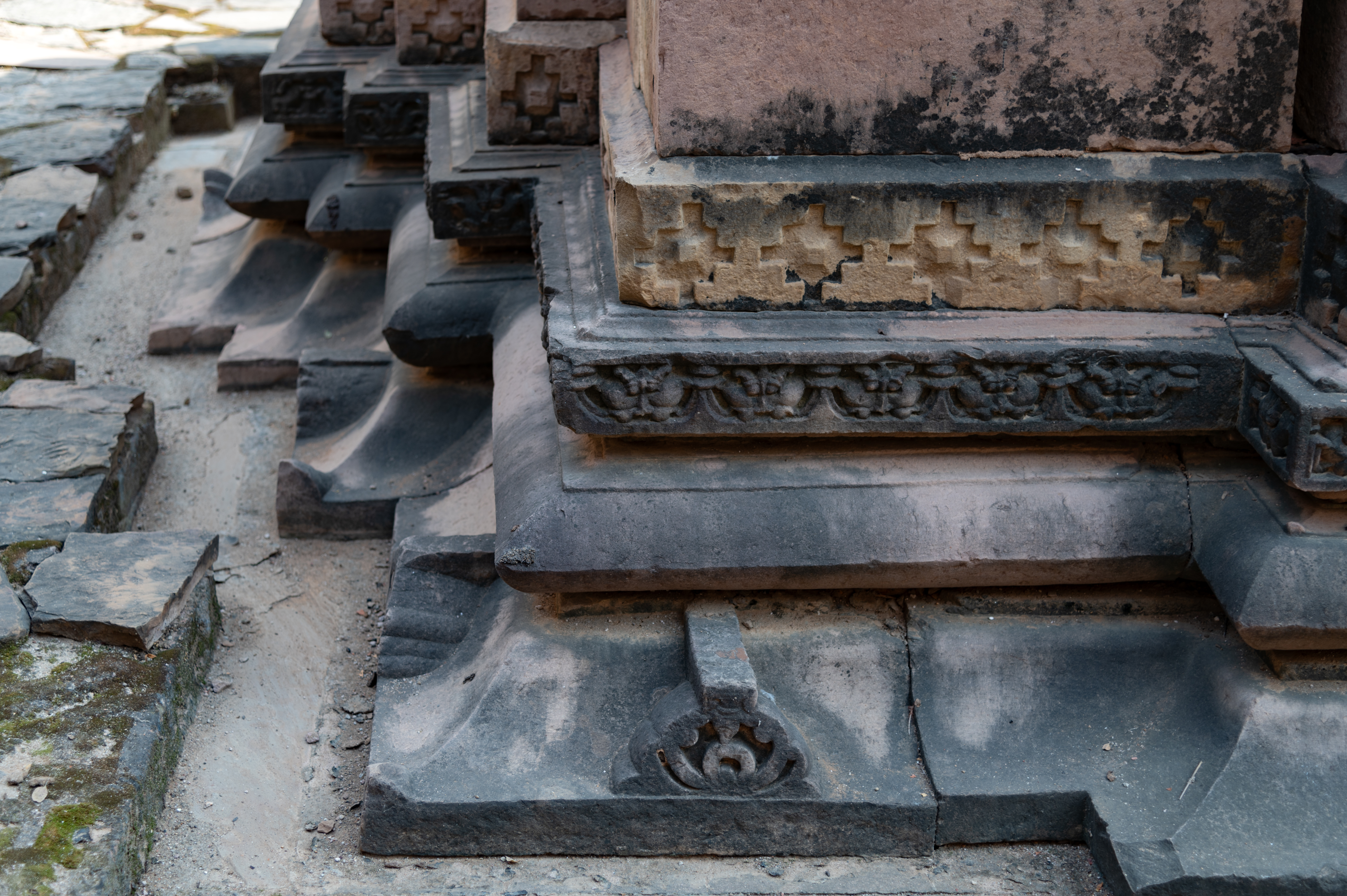 The Kaner-ki-Putli Temple is elevated on a tall vedibandha (basal mouldings). Some of the base mouldings are partially obscured at the ground due to the restoration carried out recently. These mouldings comprise kapotapalika (cyma recta), kalasha (a pitcher), grassapatta (a band of kirtimukha or face of glory), and patta (band), adorned with jala (checkered) carvings, from the bottom to the top. Positioned above these mouldings is a kumbha (pot), intricately carved with deities and a ratnapatta (diamond band). Beyond the kumbha, there are carvings of kalasha, antarapatta (recesses between mouldings), and kapotapalika.