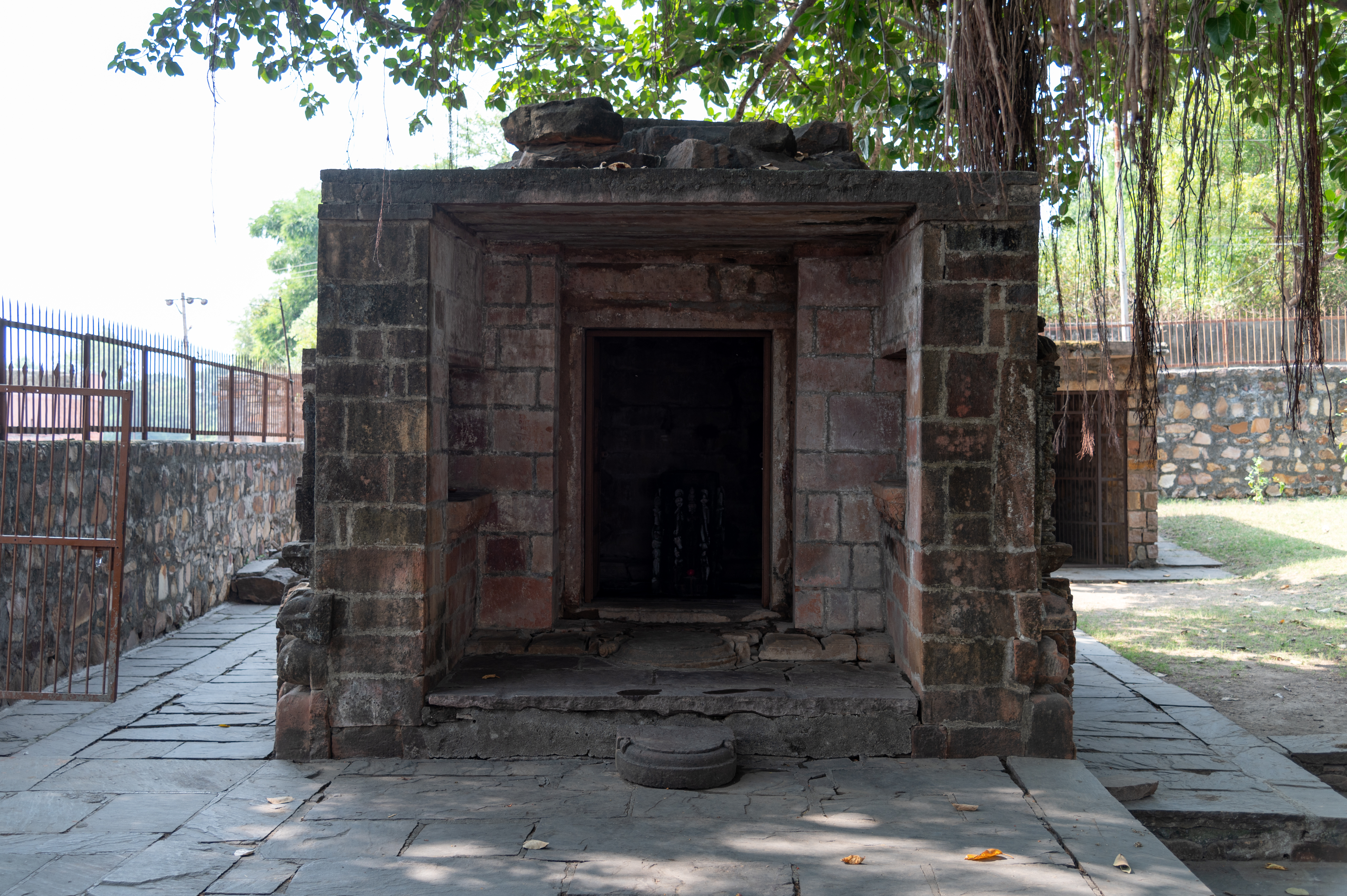 Shiva Temple 1 is located close to the revered Banyan tree. The temple is a small structure with an antarala (vestibule or antechamber) and a garbhagriha (sanctum sanctorum). The shikhara (superstructure) of the temple is in ruins.