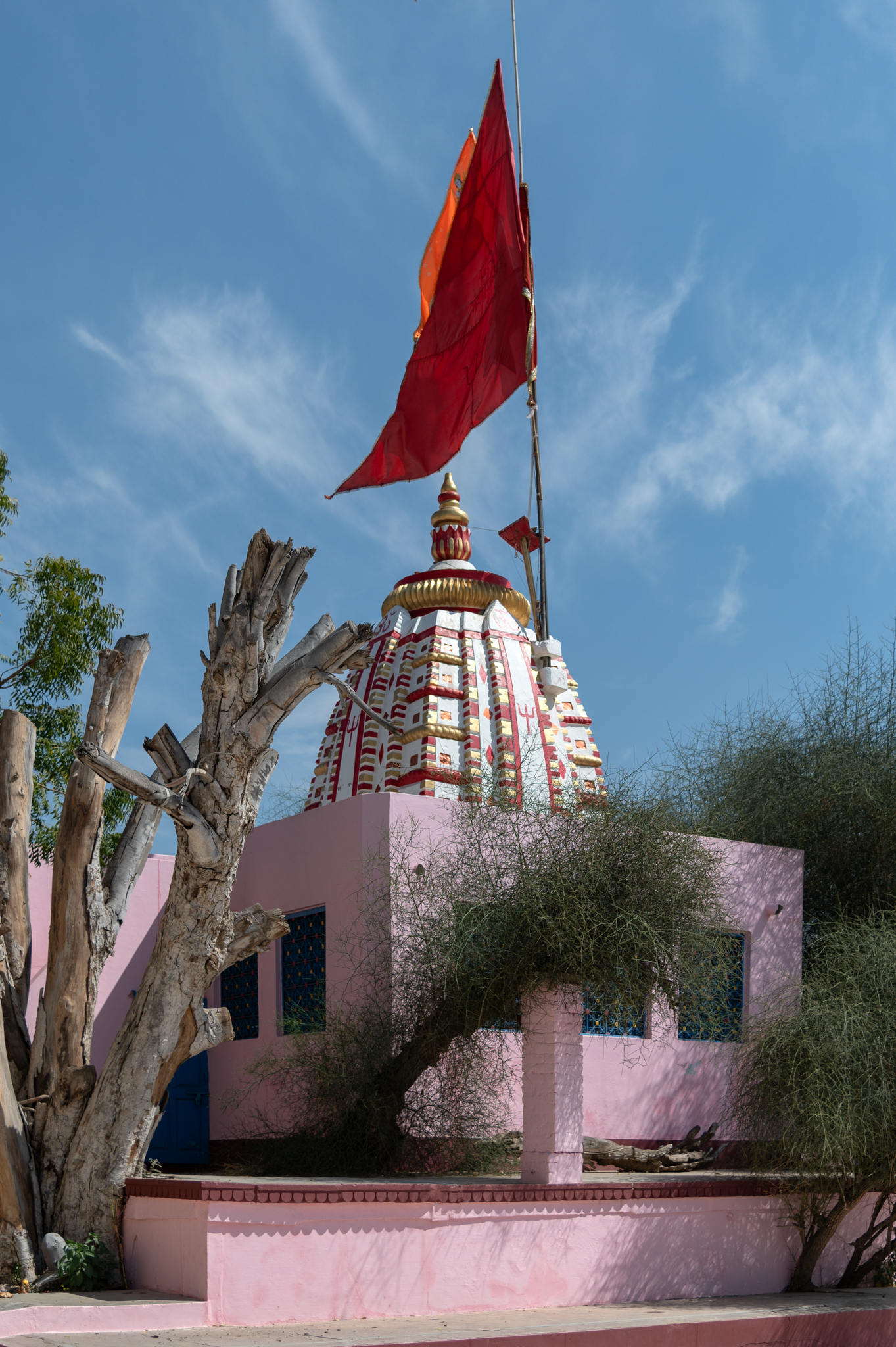 The west-facing view of the Suswani Mata Temple reveals a structure surrounded by a large courtyard. At the centre stands the old temple structure painted in white, red, and golden colours. There are a few sculptural fragments on the south side of the temple. A kera tree believed to be auspicious by the devotees of Suswani Mata is situated to the south of the temple.