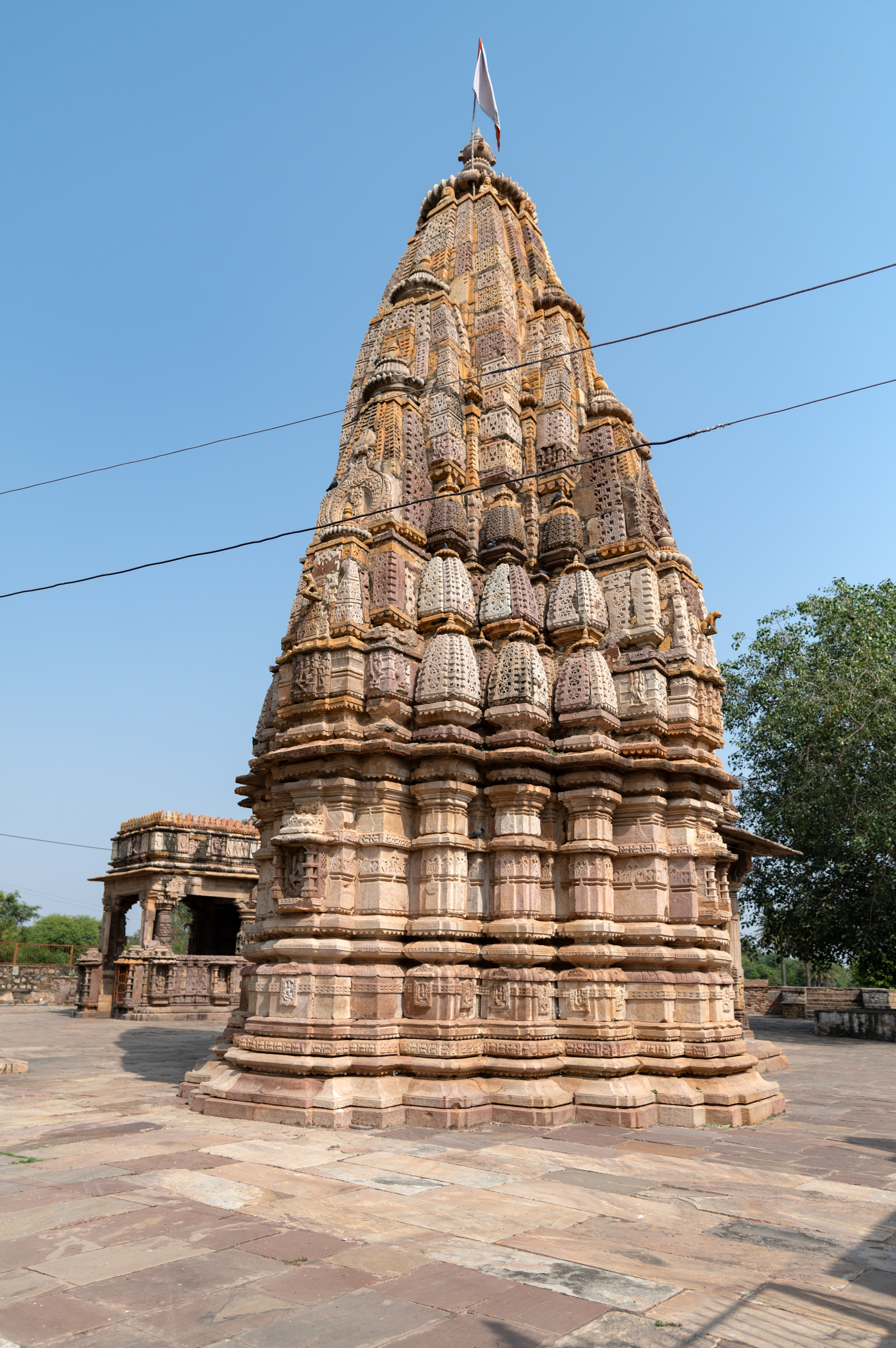 Image 16: The exterior of the Hazareshwar Temple is embellished with depictions of deities. The vedibandha (basal mouldings) has various ornamental elements including khura (hoof), kapotapalika (cyma recta),  karnika, grassapatta (a band of kirtimukhas or face of glory), plain patta, kumbha (pot), kalasha (pitcher), garggarika (decorative motif comprising arrow between two spirals), and kapotapalika. On the jangha are bhadras (central offsets) on all three sides, with the space between them adorned with stambhas (buttresses) featuring motifs of peepal leaves and grassapatta. Rising above the jangha is the majestic shikhara (superstructure).