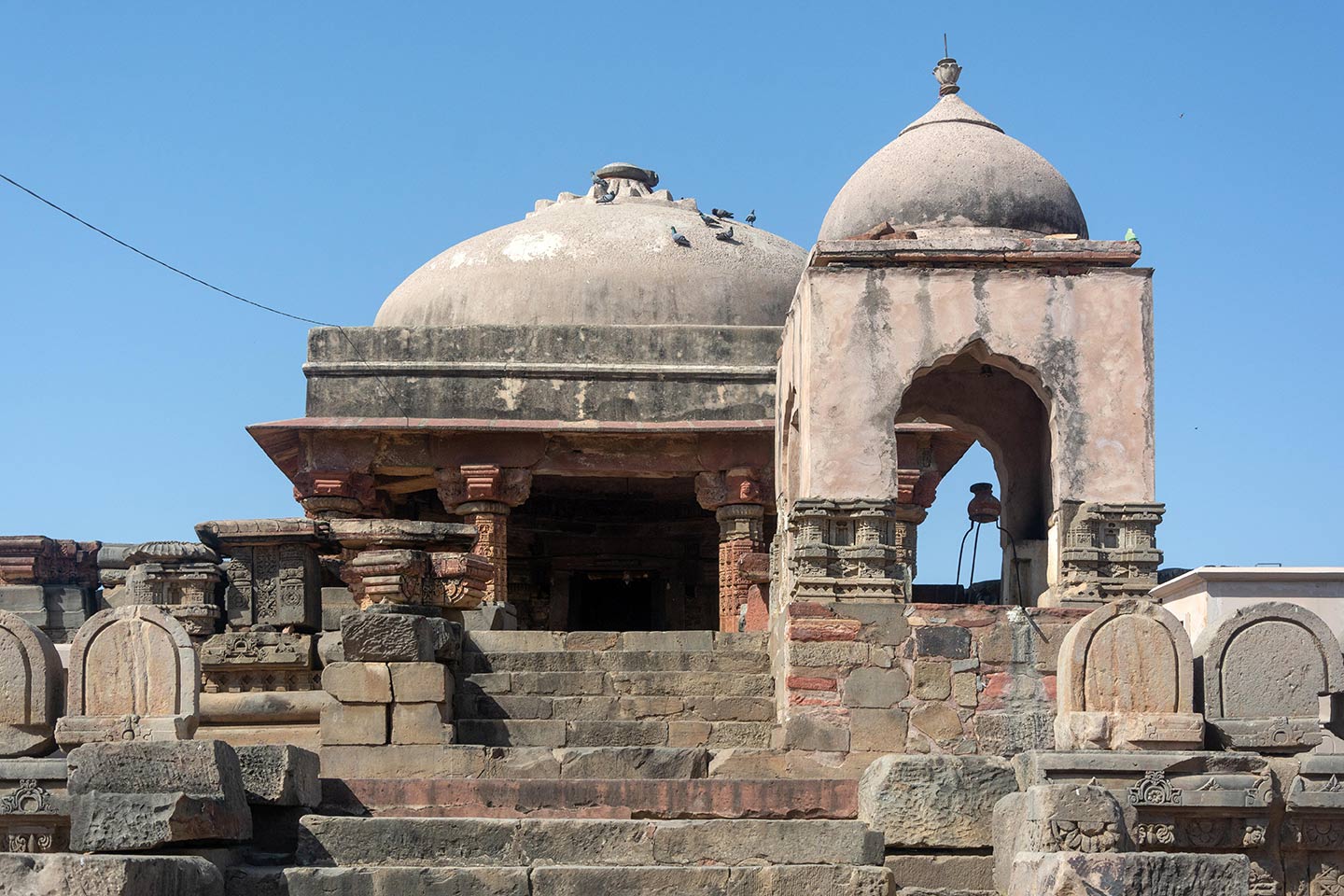 The Harshat Mata Temple and Nandi shrine can be seen from the front (east). During the temple's reconstruction, the circular domed structure replaced the destroyed original stone temple in the Mahameru style.