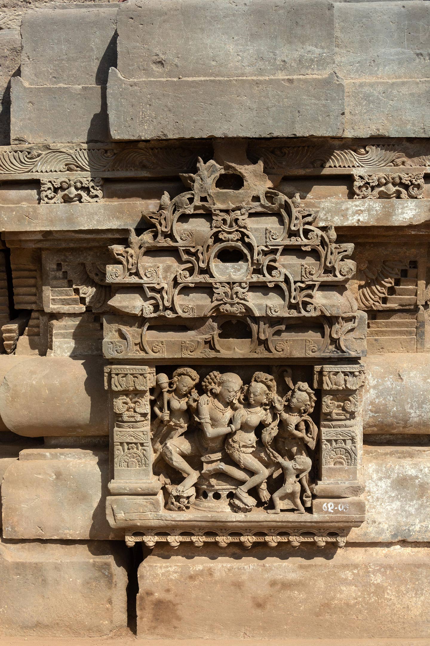 Panels with pillars and tiered shikhara featuring gavaksha (horseshoe) motifs frame couples invoking shringara rasa, which is associated with romance, love, and attractiveness between lovers. Unlike other parts of the temple, the faces remain intact, and their heavy jewellery, elaborate headgear, and garments indicate their royalty or high social class affiliation.