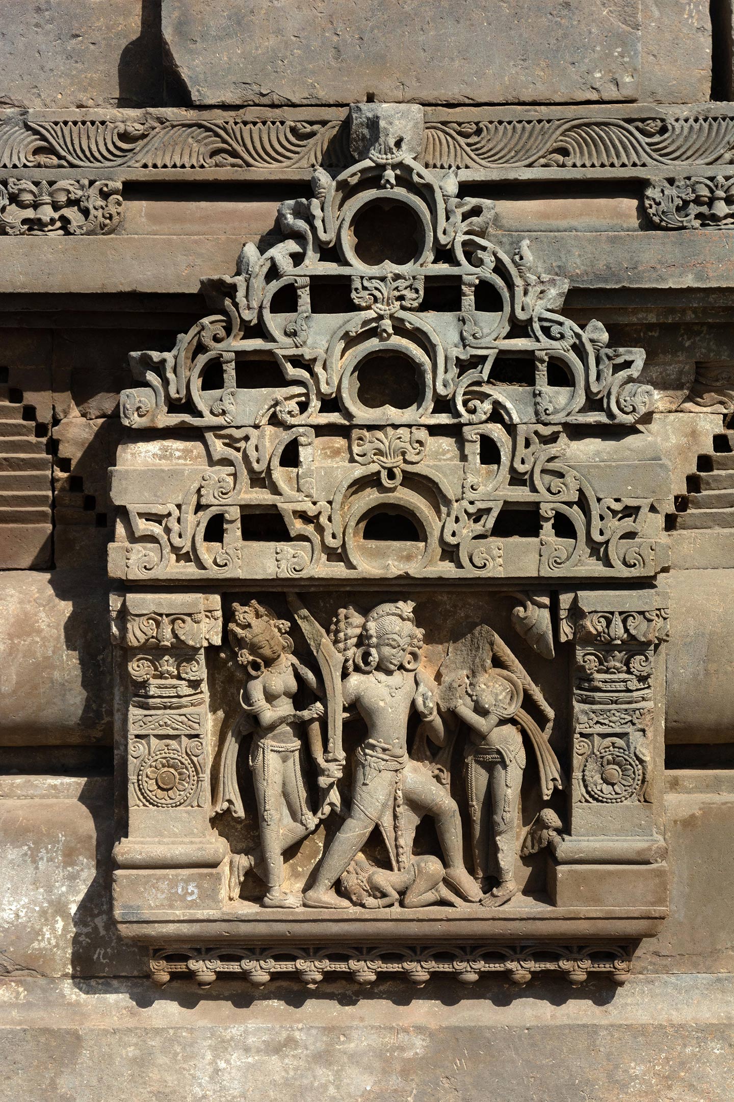 This panel depicts a warrior invoking raudram rasa (fury/rage) by aggressively wielding a drawn sword. The central figure, a warrior king, is aggressively stepping forward, wielding a naked sword in his right hand. He tucks a dagger into his kamarbandha (waist belt). The central female figure (seen on the left) may be a queen, who is trying to stop the man by pulling him behind.