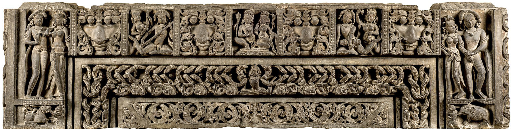 Image 7: It is a trishakha (three vertical bands or branches) lintel having a nagashakha (serpent branch), inner patravalli (foliage pattern), and a mithunashakha (amorous couple branch) at the top, with the central figure of Shiva-Parvati in an alingana (embrace), interspersed by kirtimukhas (face of glory).