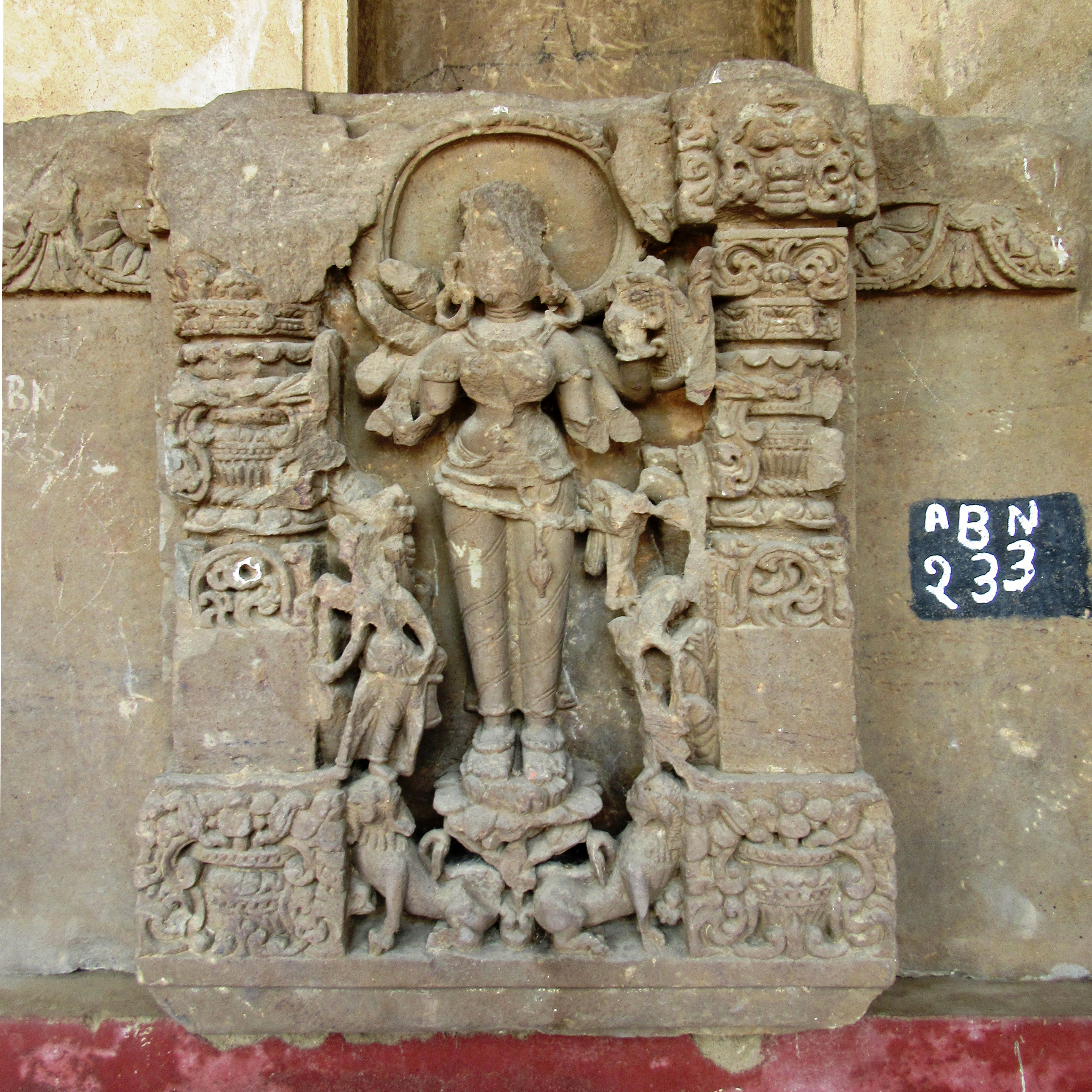 Image 8: The image depicts an eight-armed deity standing in samabhanga (upright posture) on a lotus, beneath which are two addorsed lions. The deity grasps a shield in her upper left hand, while her remaining hands remain broken. Behind her head, there is a halo.